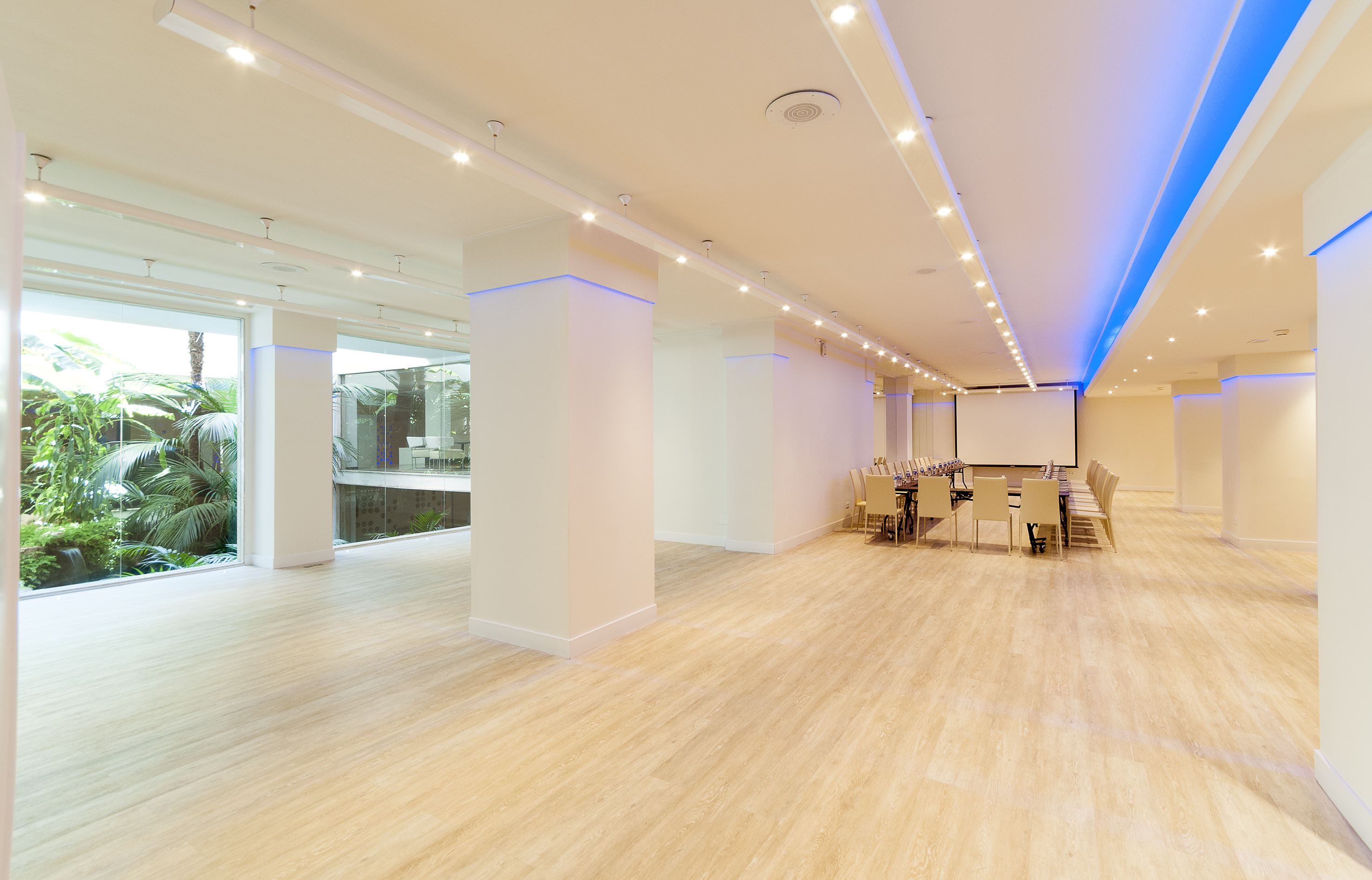 Modern conference room with large windows, wood floor, and meeting setup.
