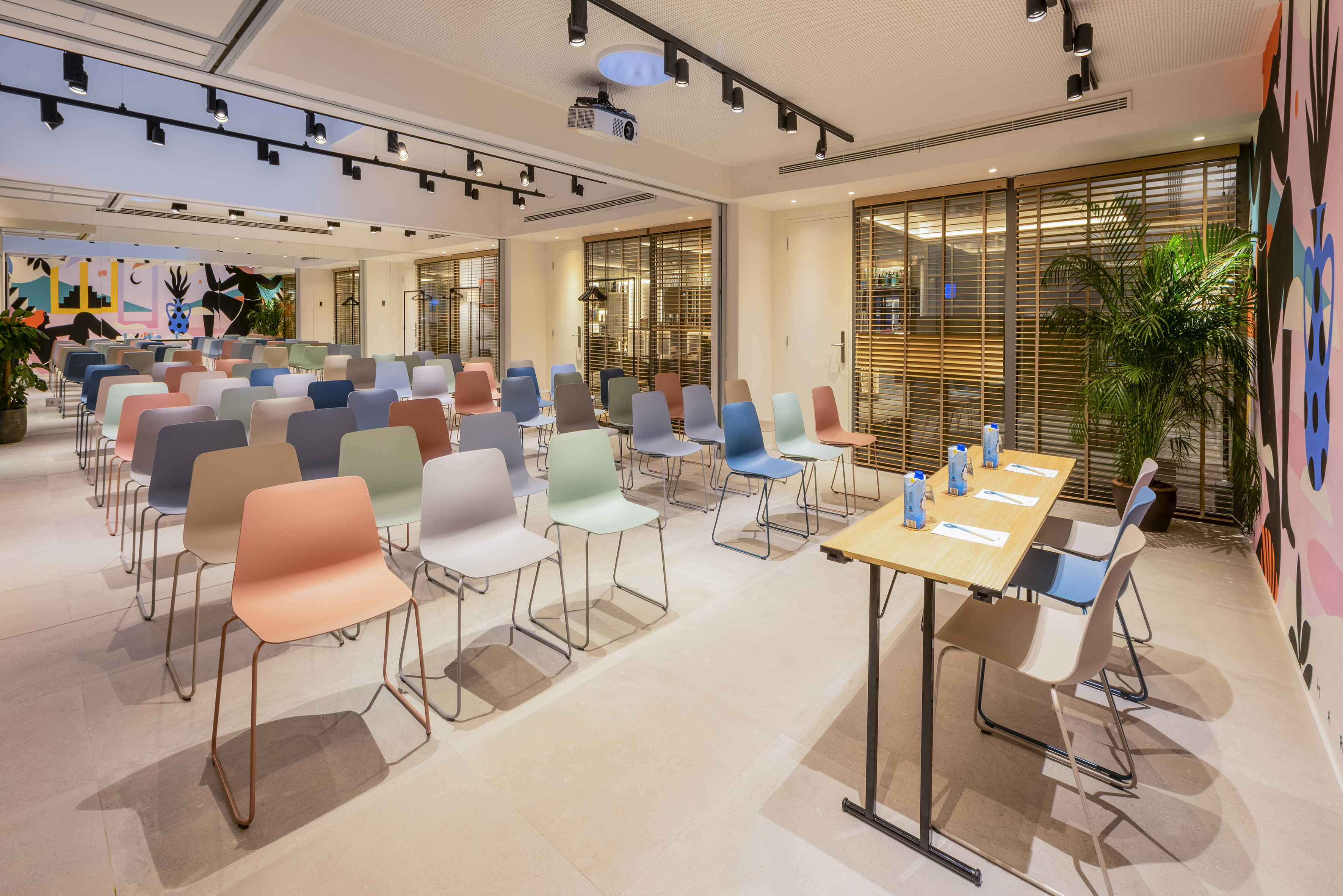 Modern conference room with colorful chairs, projector, and abstract wall art.