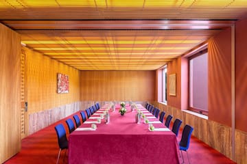 a long table with red tablecloth and blue chairs