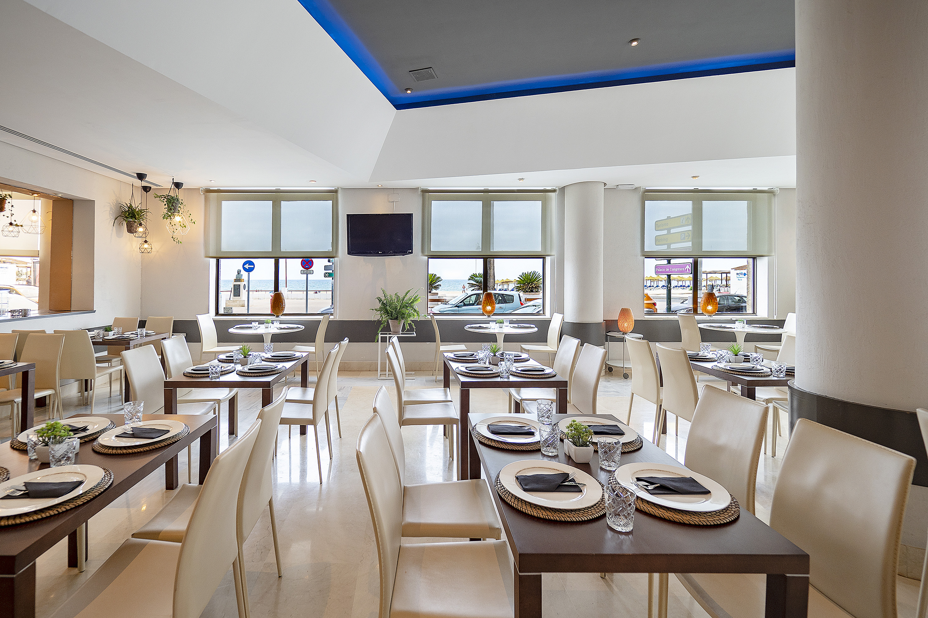 Modern coastal restaurant interior with set tables.