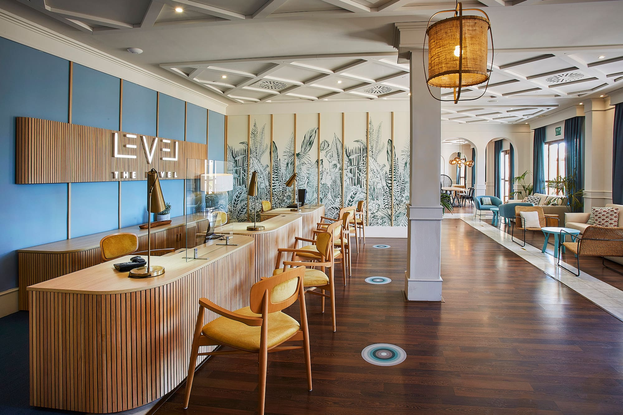 Modern hotel reception desk at "The Level" with botanical wall art.