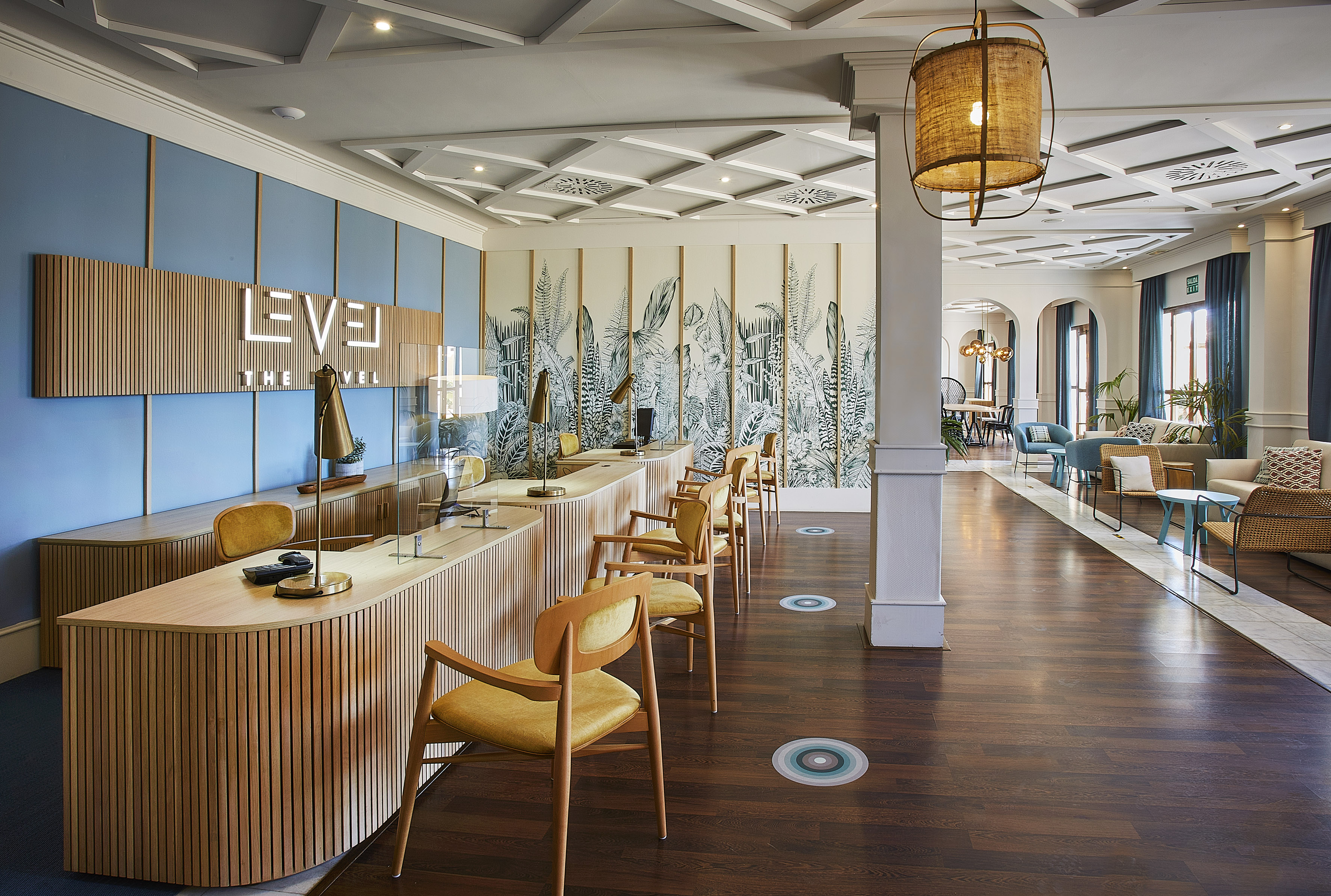 Modern hotel reception desk at "The Level" with botanical wall art.
