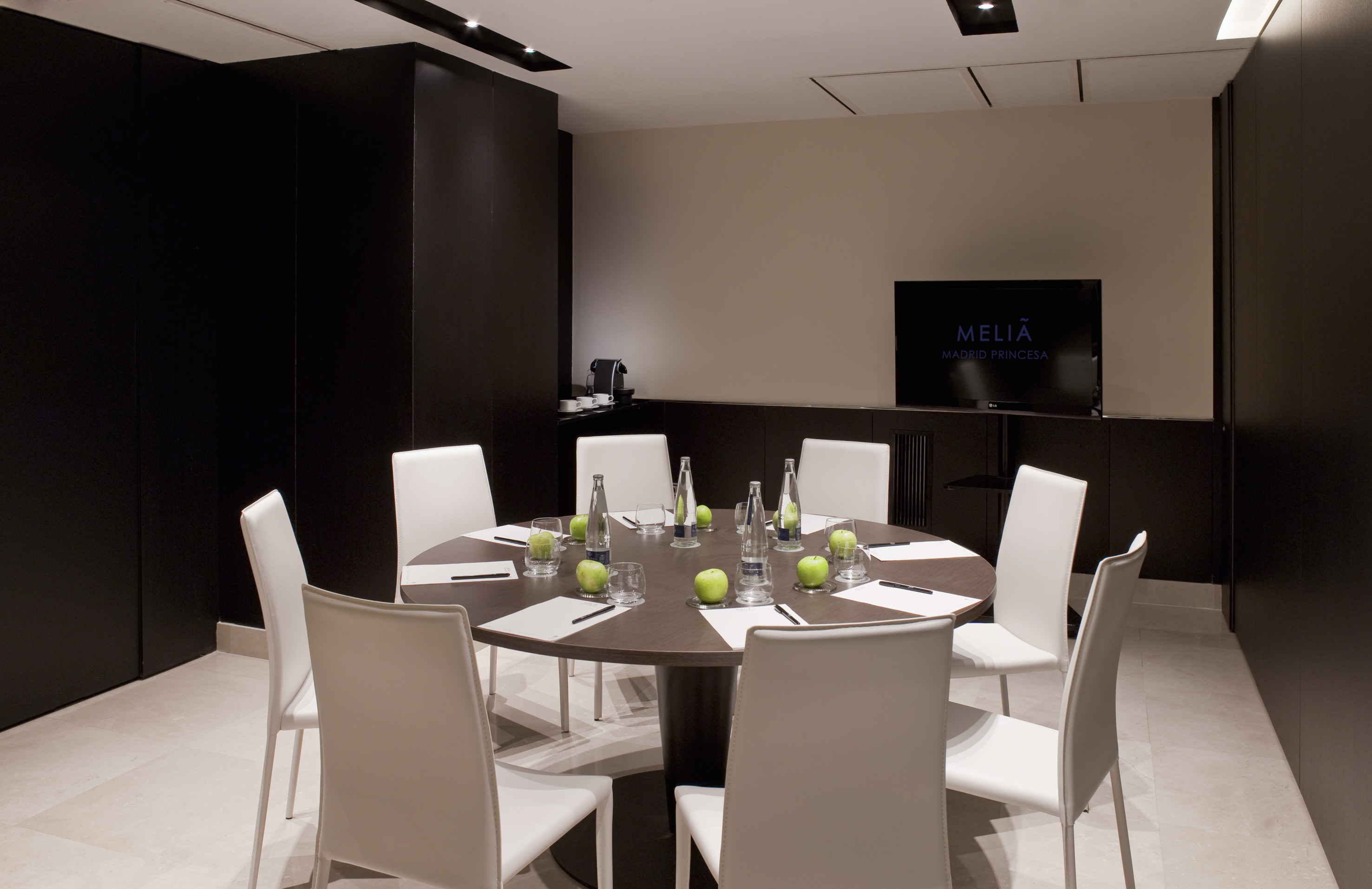 Meliá Madrid Princesa modern meeting room with round table, white chairs, and TV.