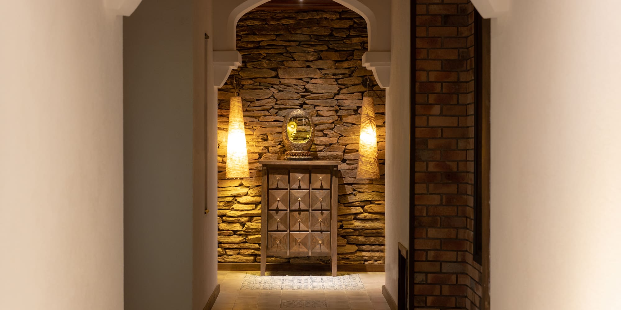a hallway with a stone wall and a mirror
