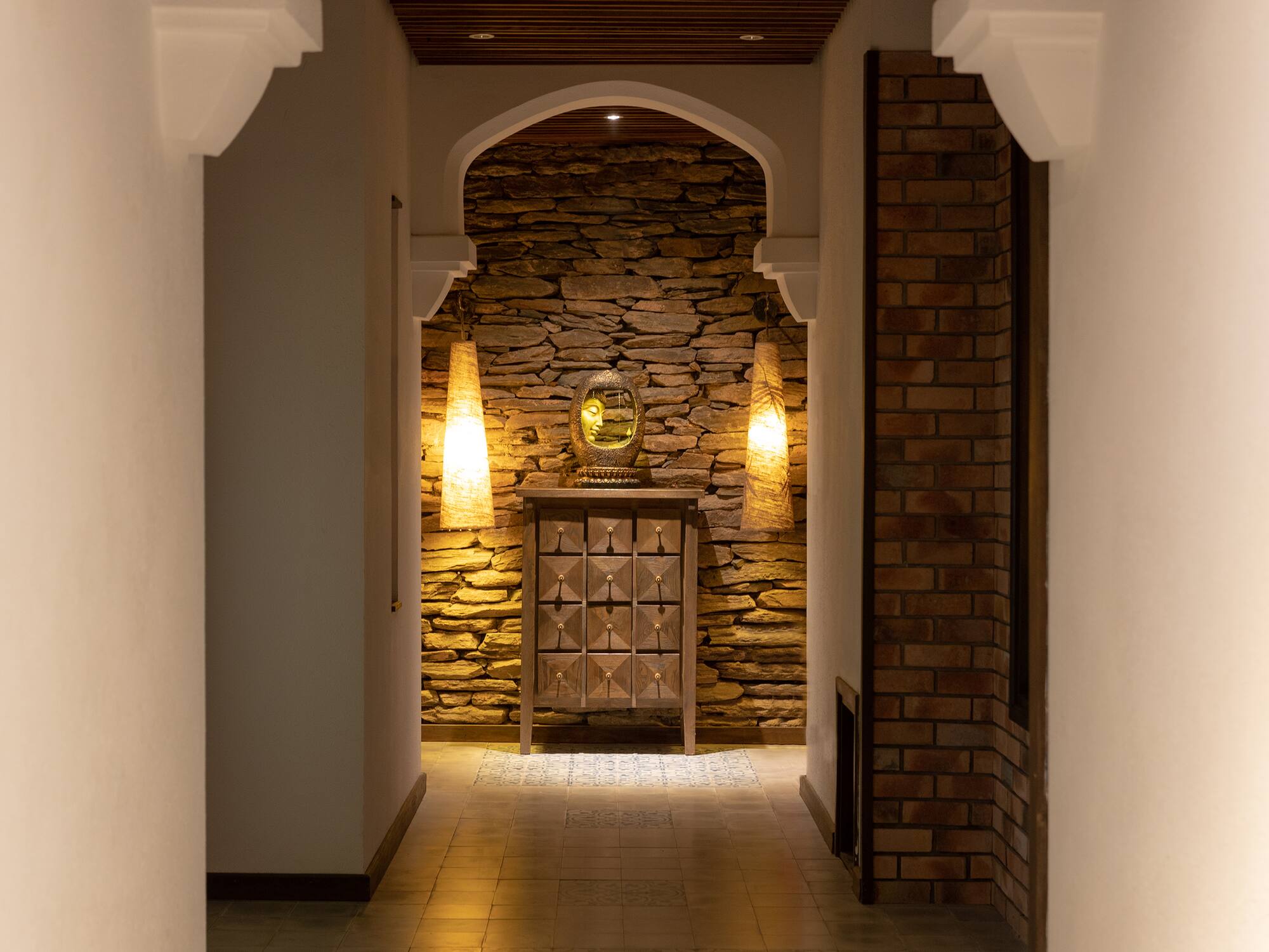 a hallway with a stone wall and a mirror
