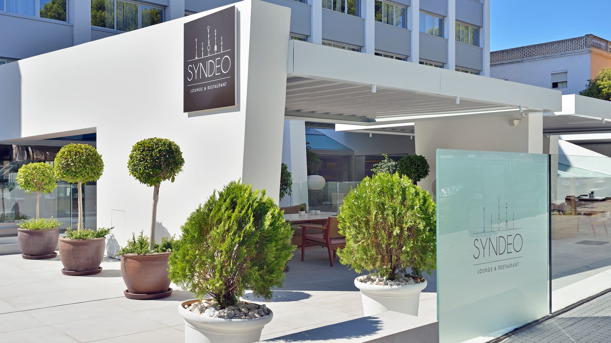 a building with a sign and plants in pots