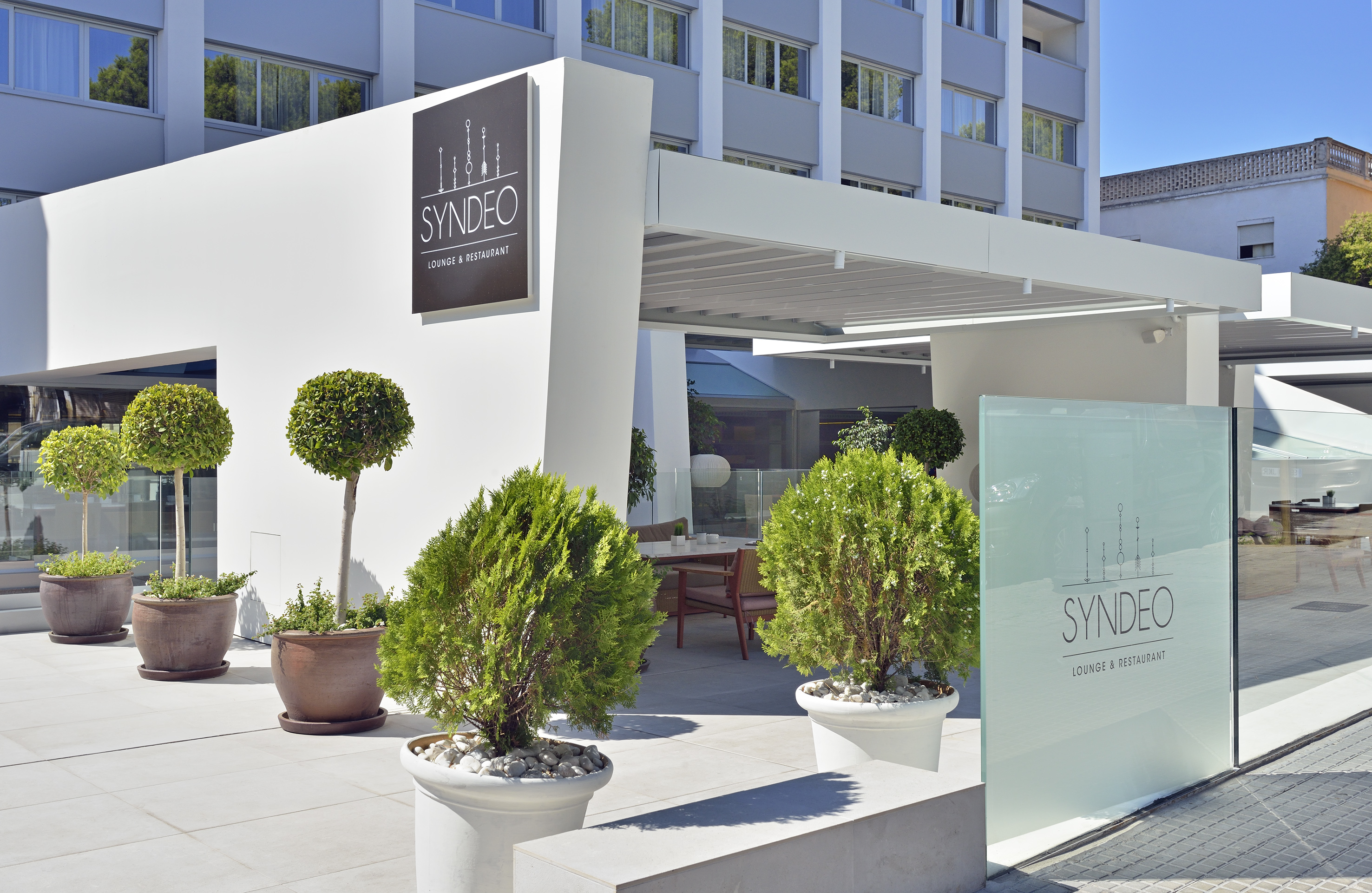 a building with a sign and plants in pots