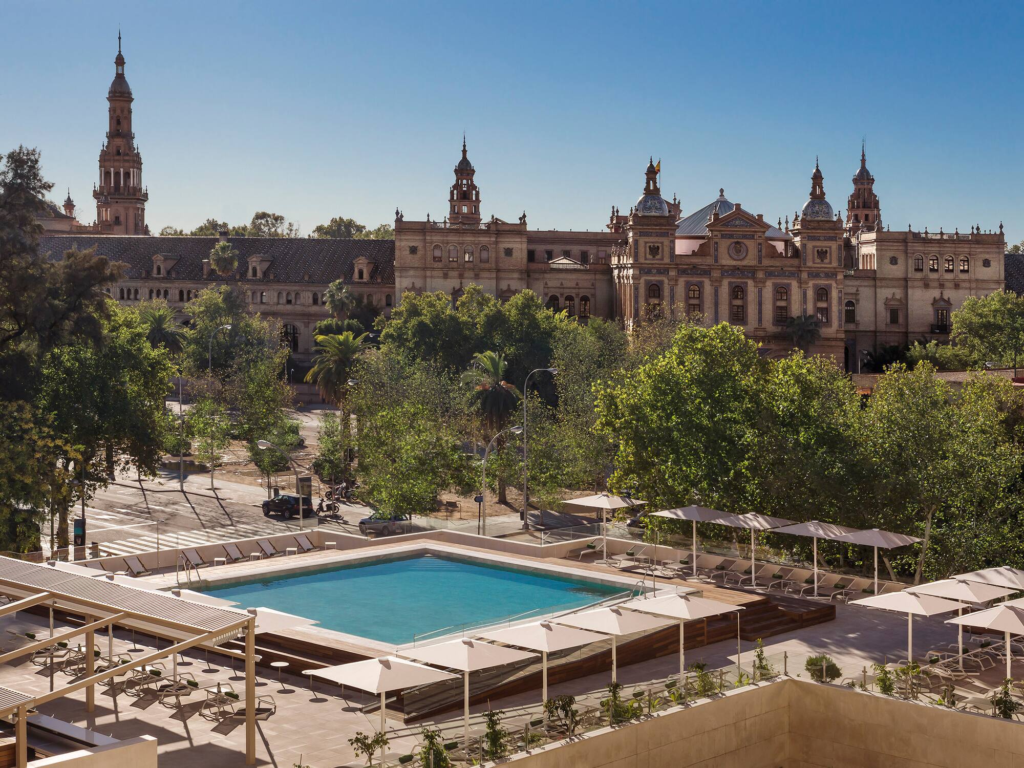 a pool in a courtyard with trees and a building in the background