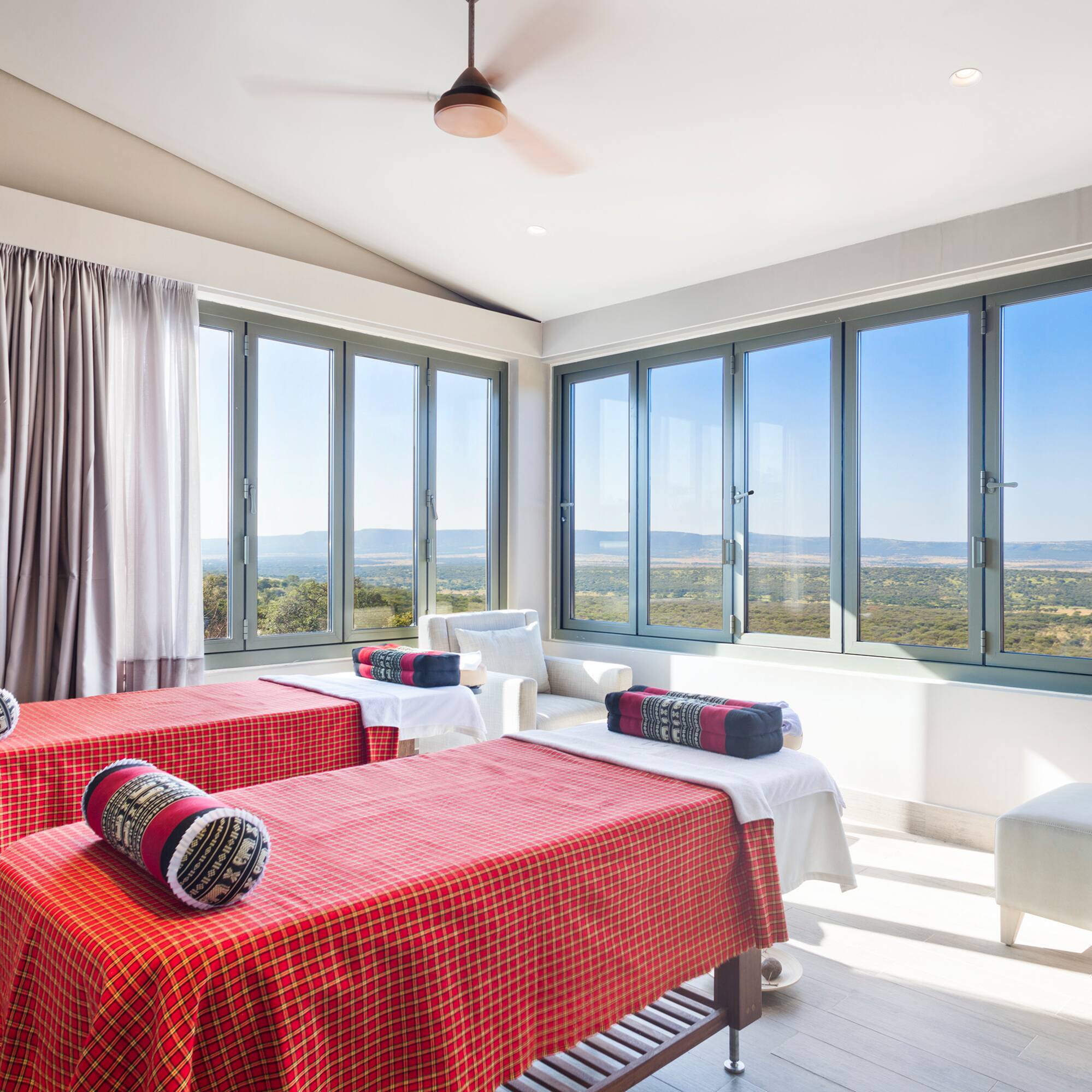 a room with red and white beds and windows