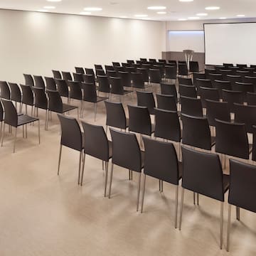 a room with rows of chairs and a projector screen