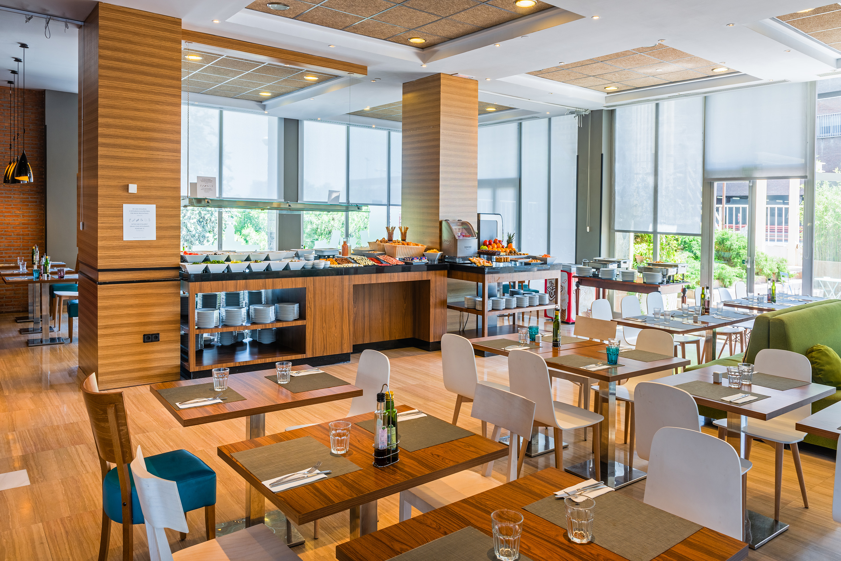 Modern hotel restaurant buffet with set tables and large windows.