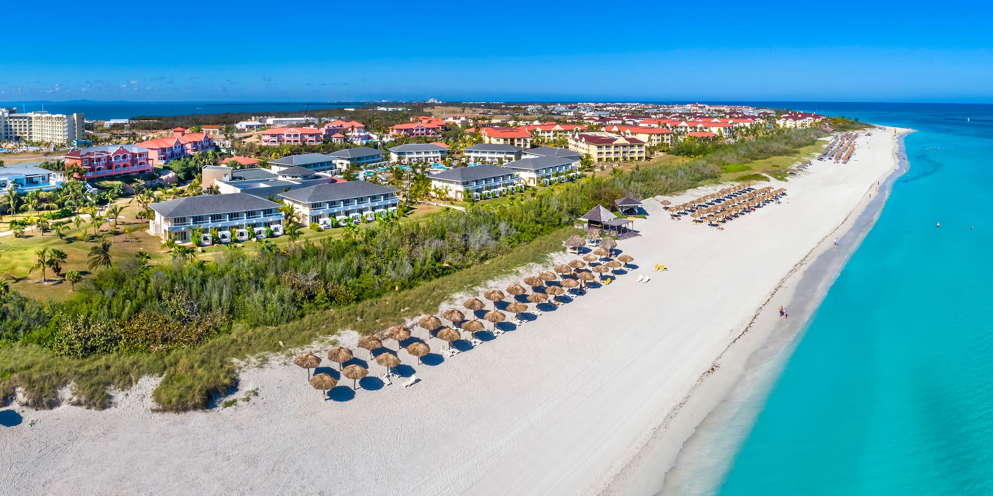 a beach with many umbrellas and buildings