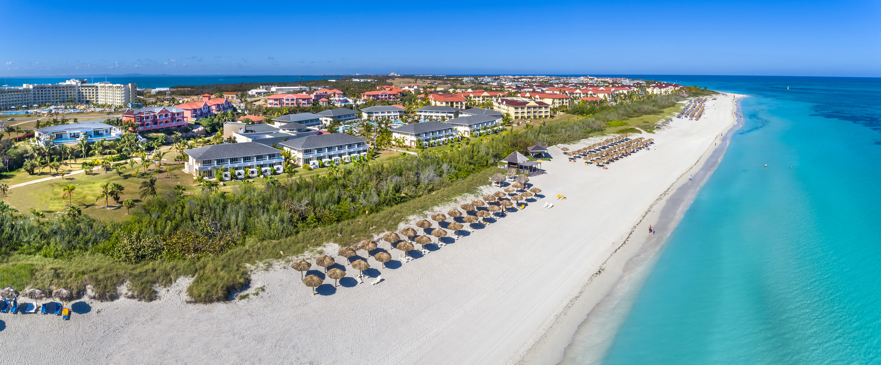 a beach with many umbrellas and buildings