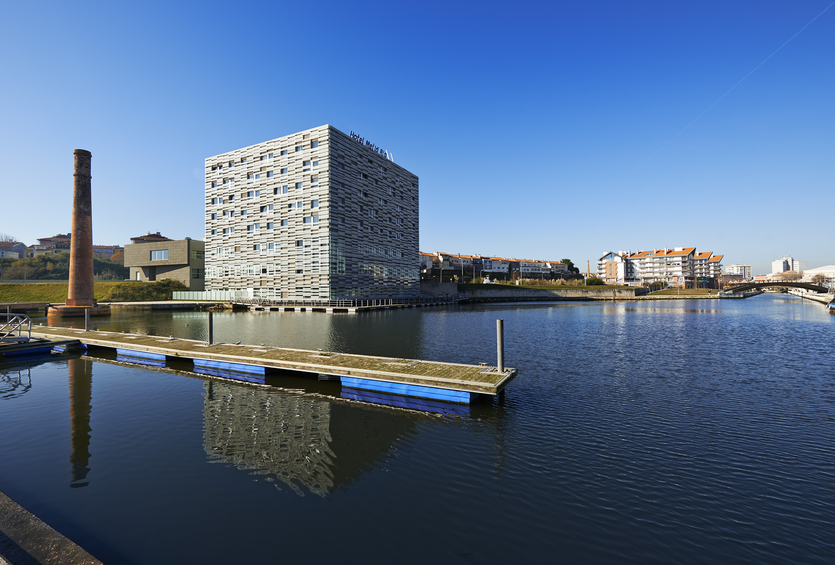 Meliá Ria Hotel and brick chimney by canal with floating dock.