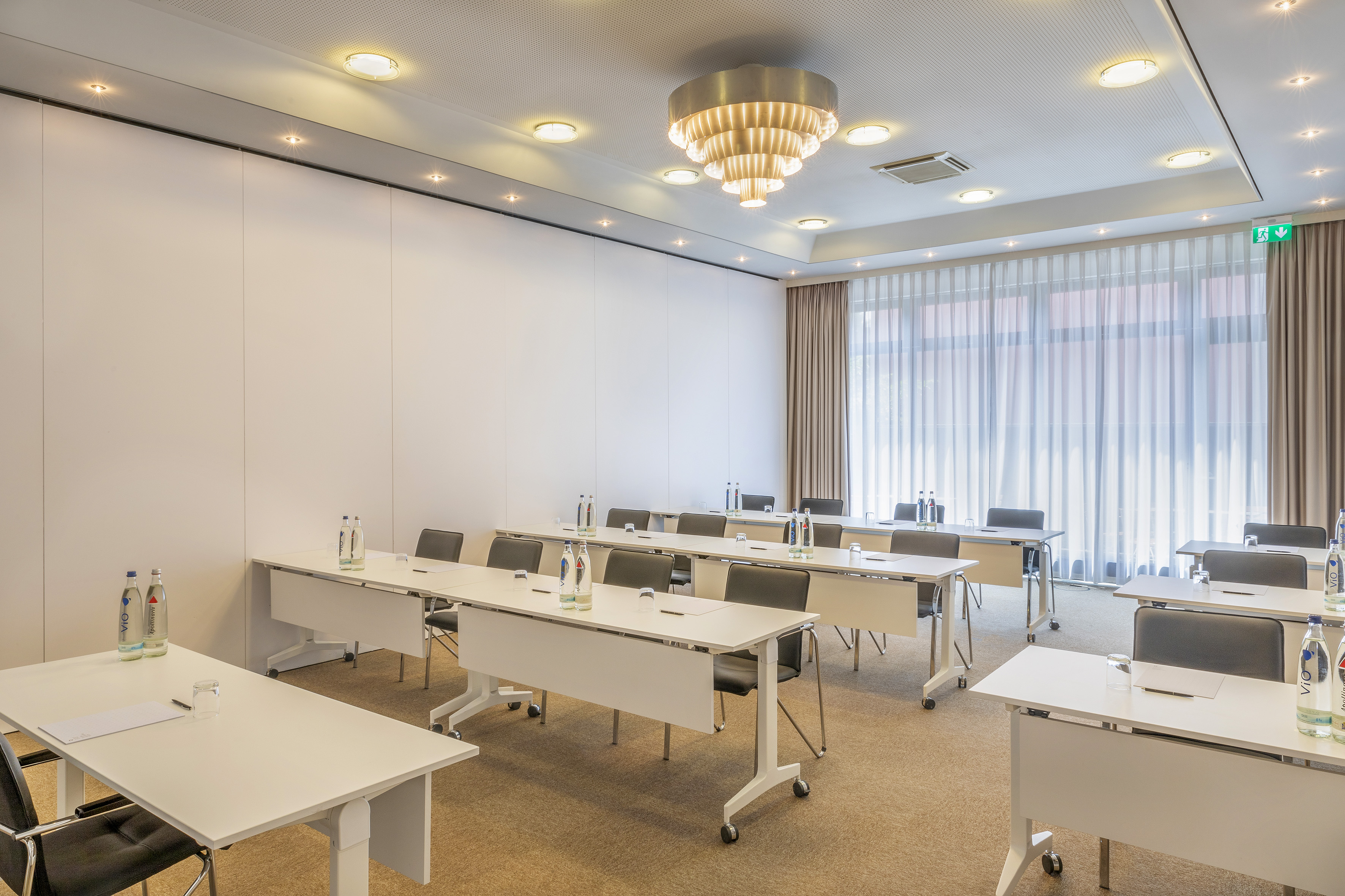 Modern conference room, classroom setup with tables, chairs, and bright lights.