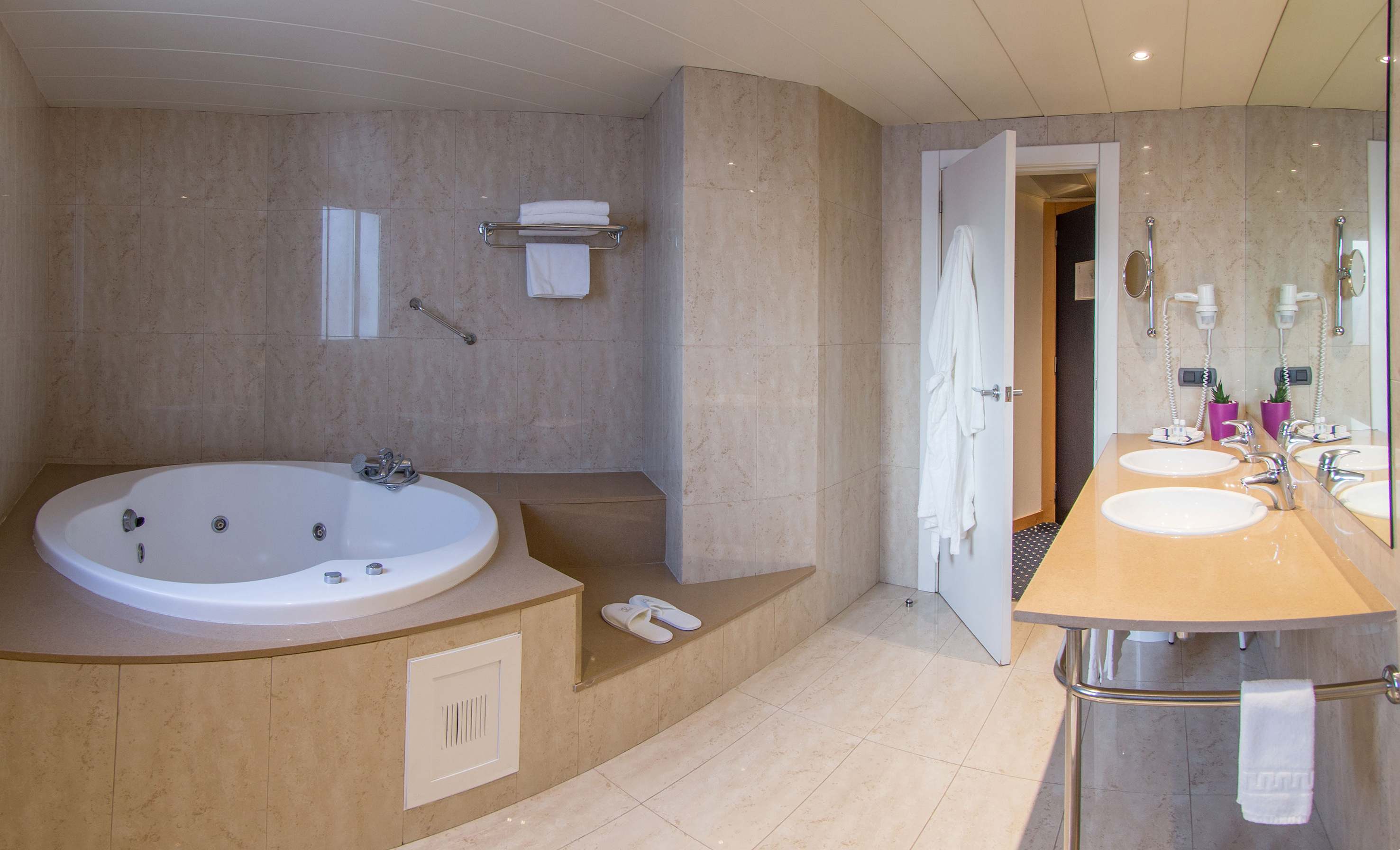 Luxurious tiled bathroom with large jacuzzi tub and double sinks.