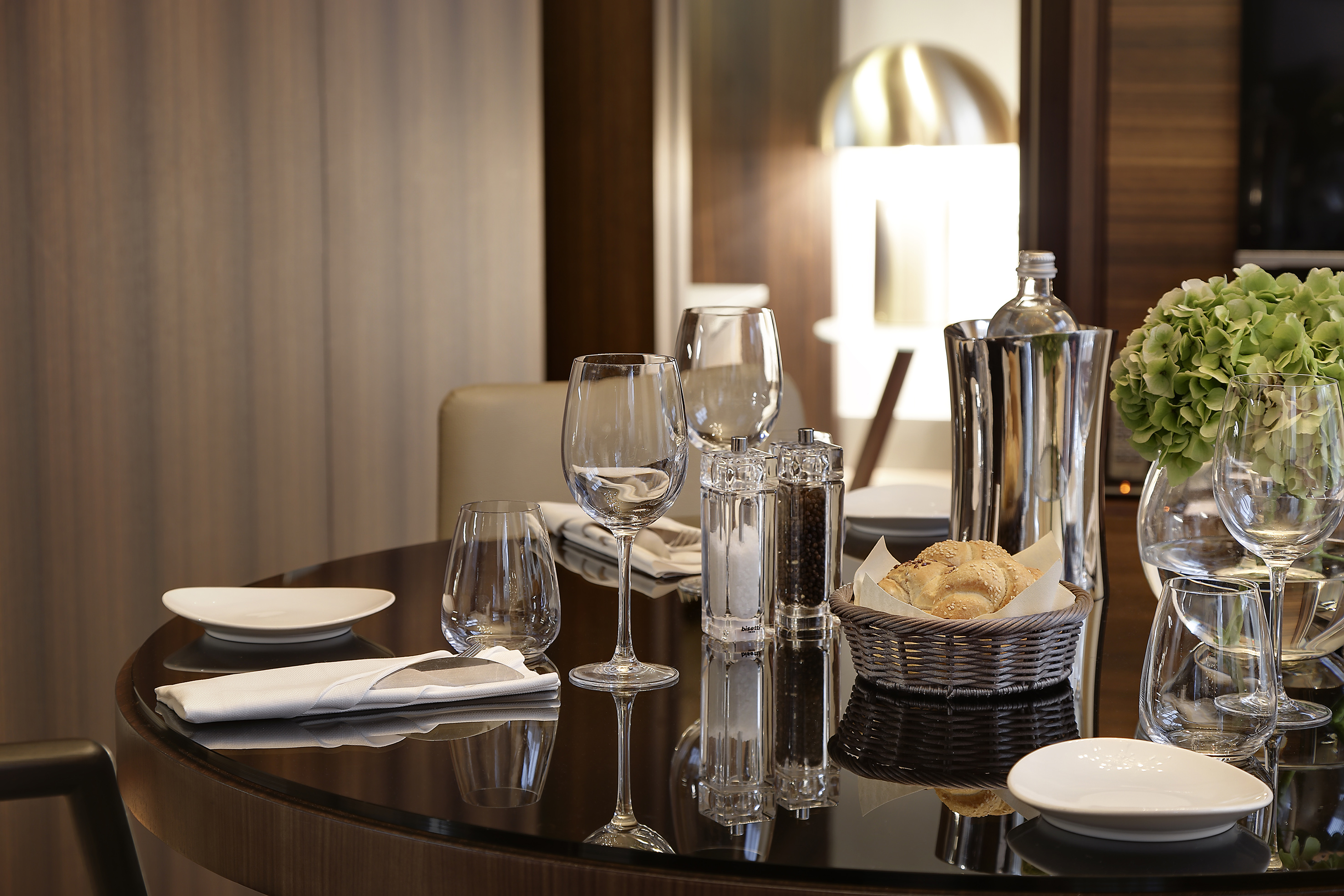 Elegant dining table with glassware, fresh bread, and salt/pepper shakers.