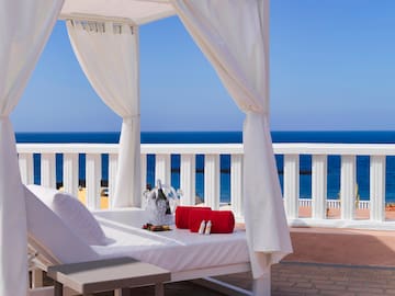 a white canopy bed with a glass vase and towels on it