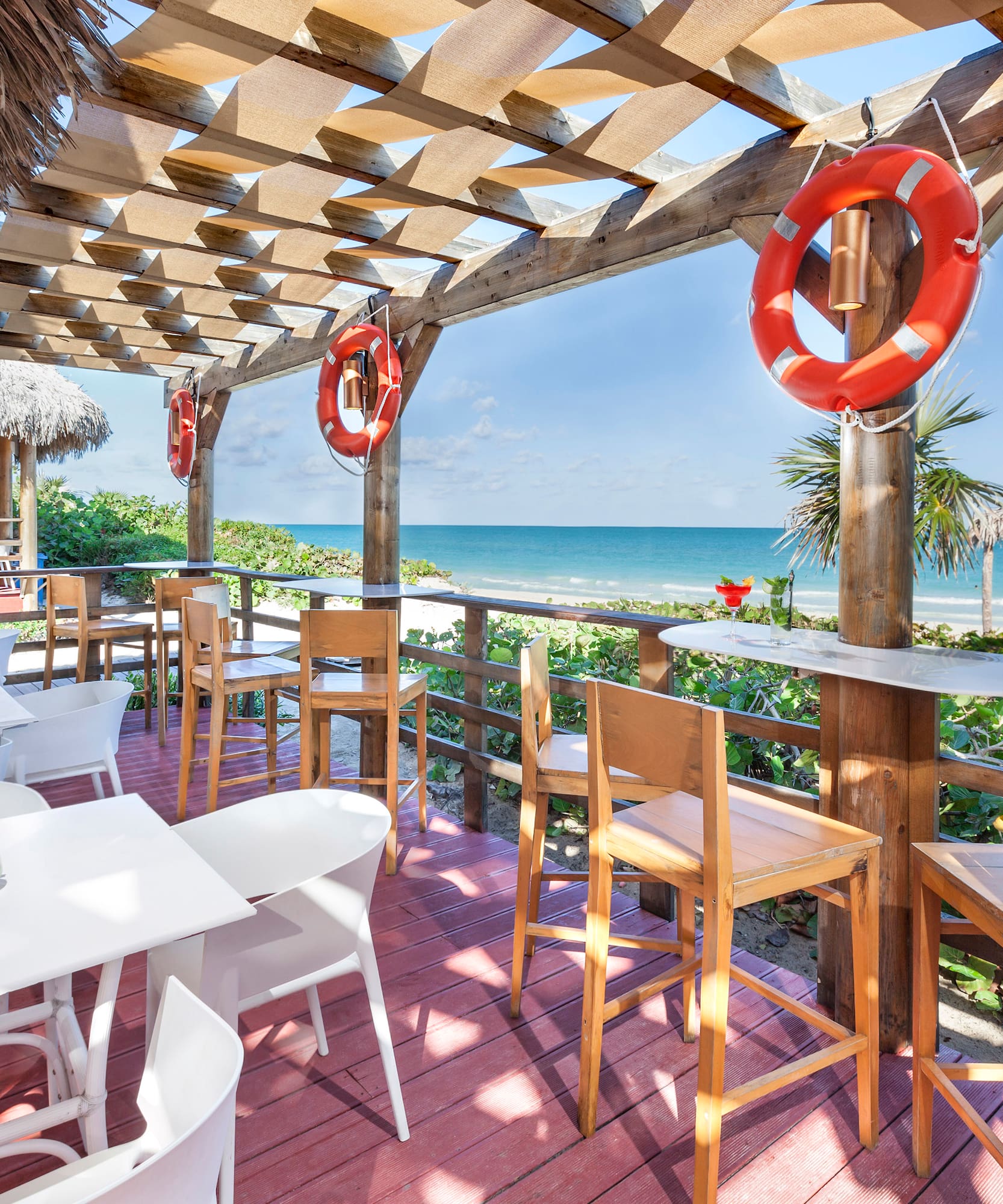 a patio with tables and chairs and a beach view