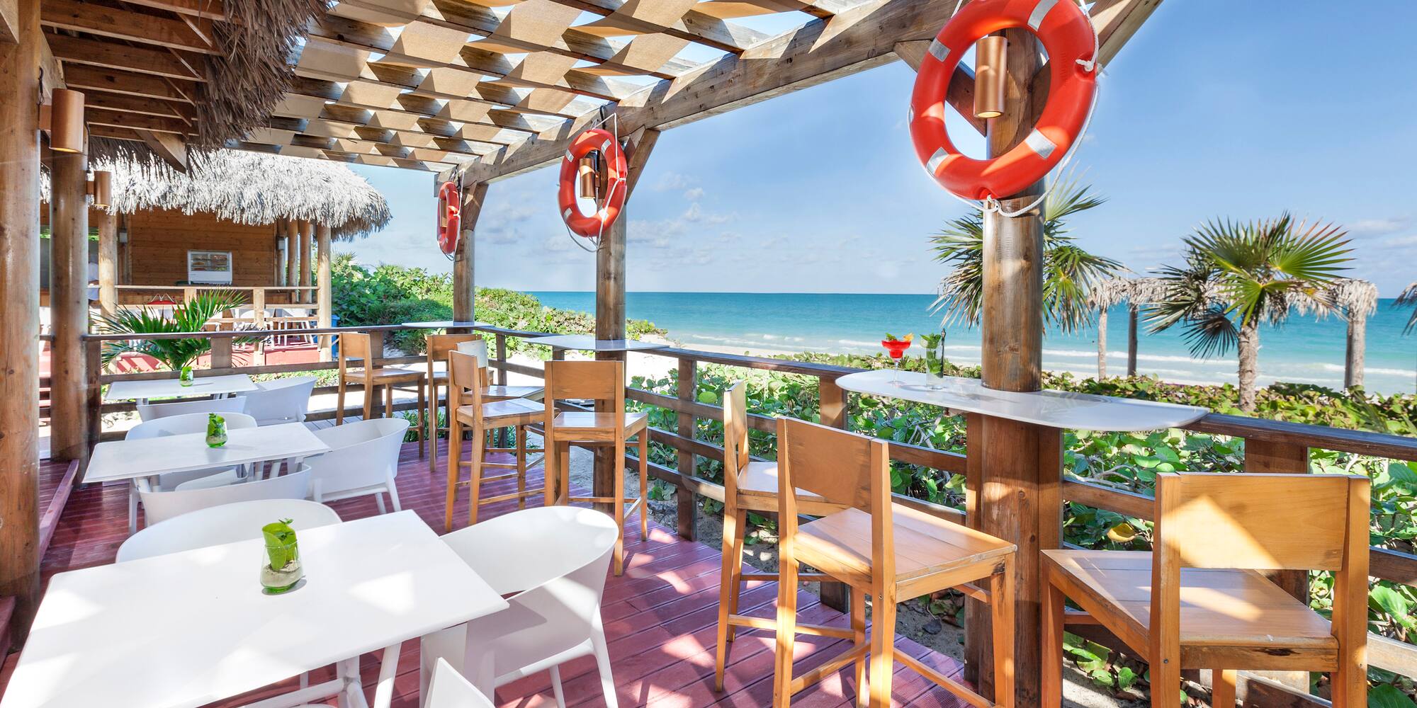 a patio with tables and chairs and a beach view