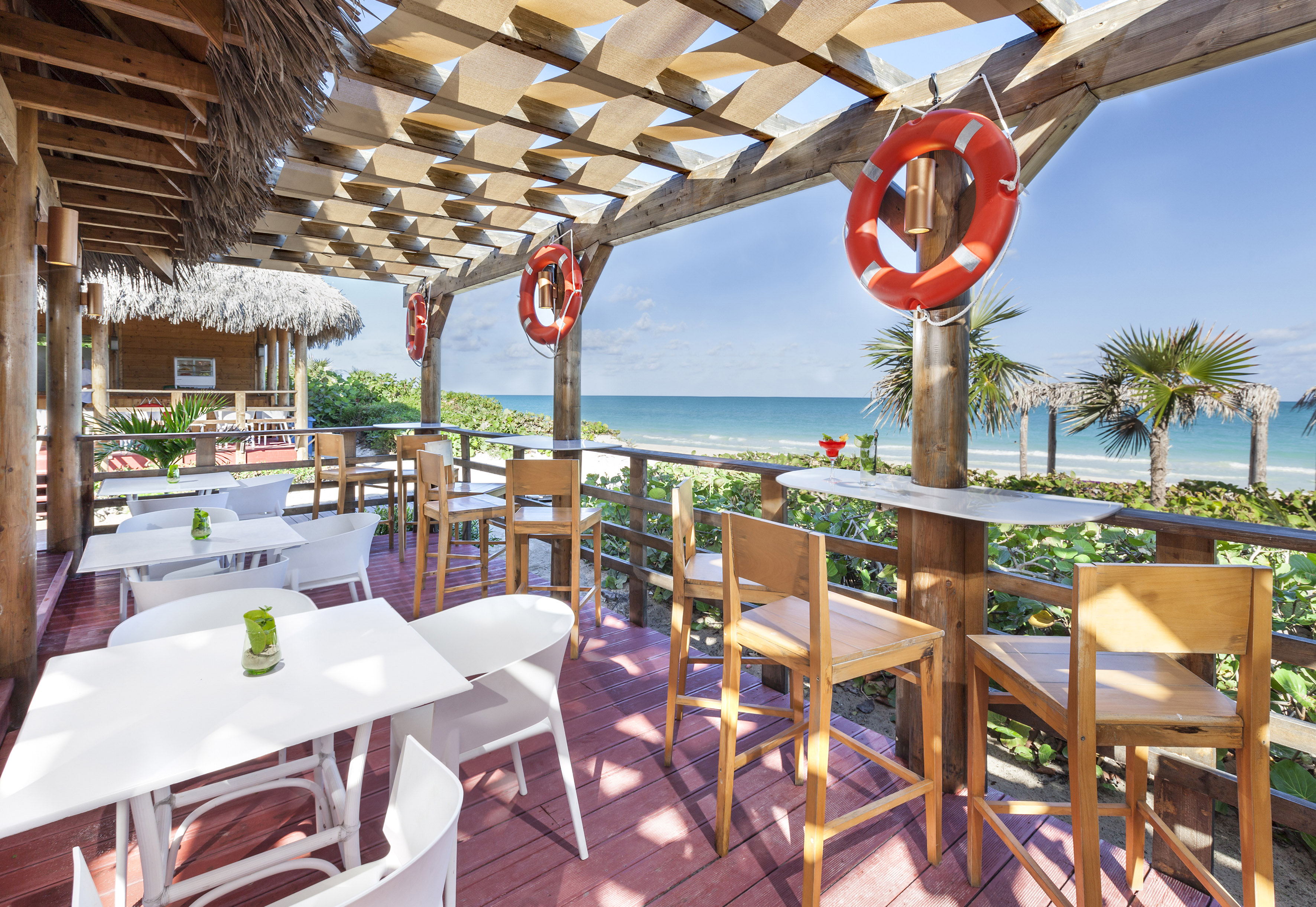 a patio with tables and chairs and a beach view