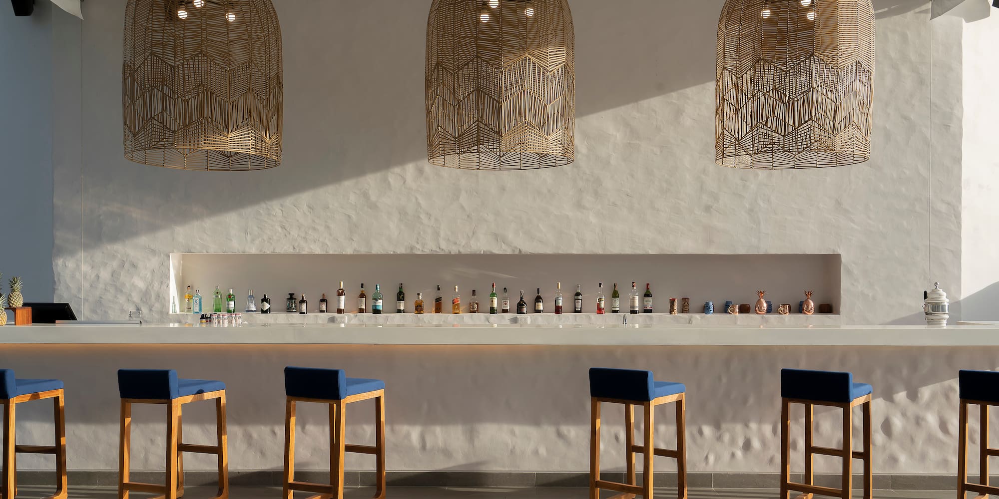 a bar with blue chairs and a row of bottles