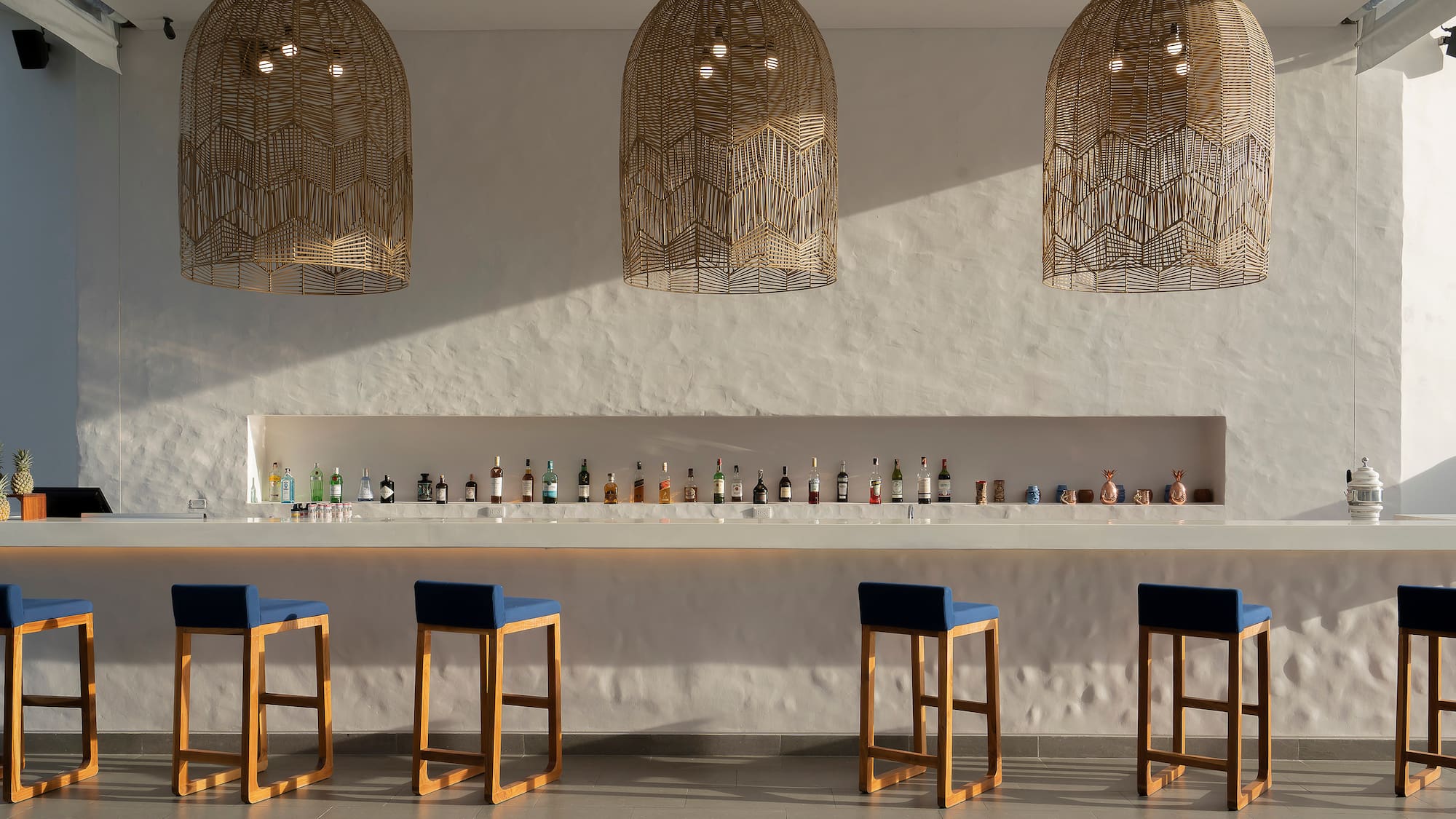a bar with blue chairs and a row of bottles
