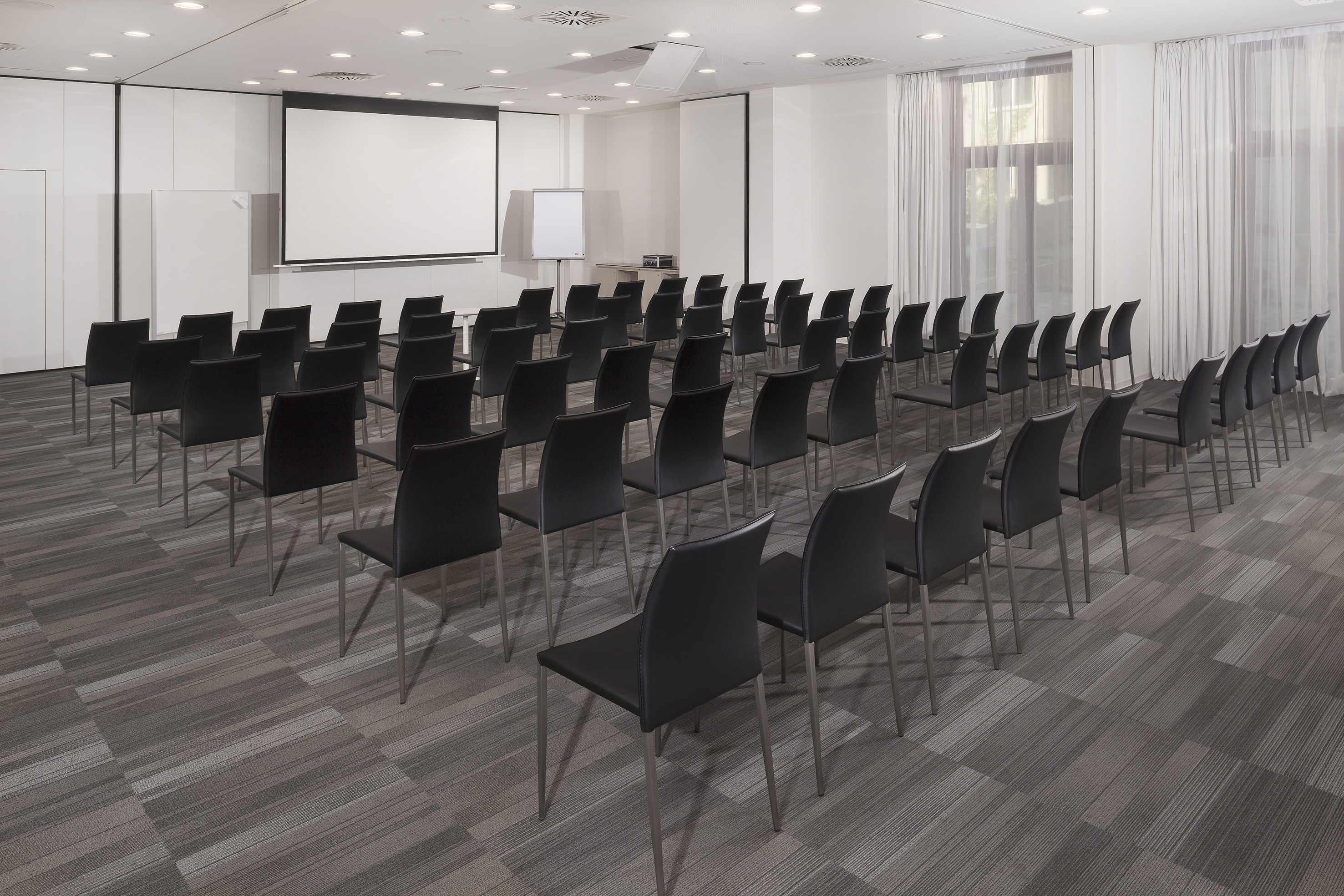 Conference room with black chairs, projector screen, and whiteboard.