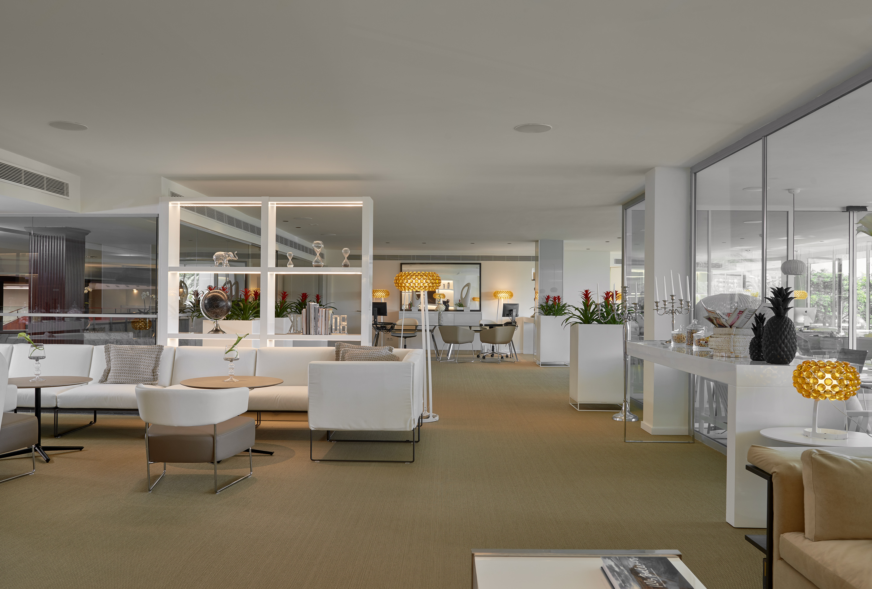 Modern hotel lounge with white sofas, golden lamps, and stylish decor.