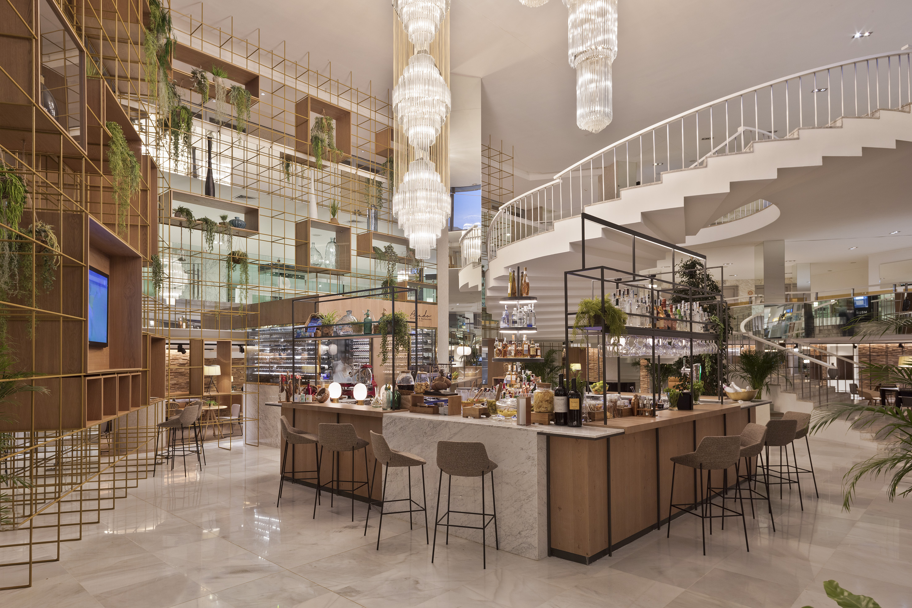 Elegant hotel bar with spiral staircase, chandeliers, and modern design.