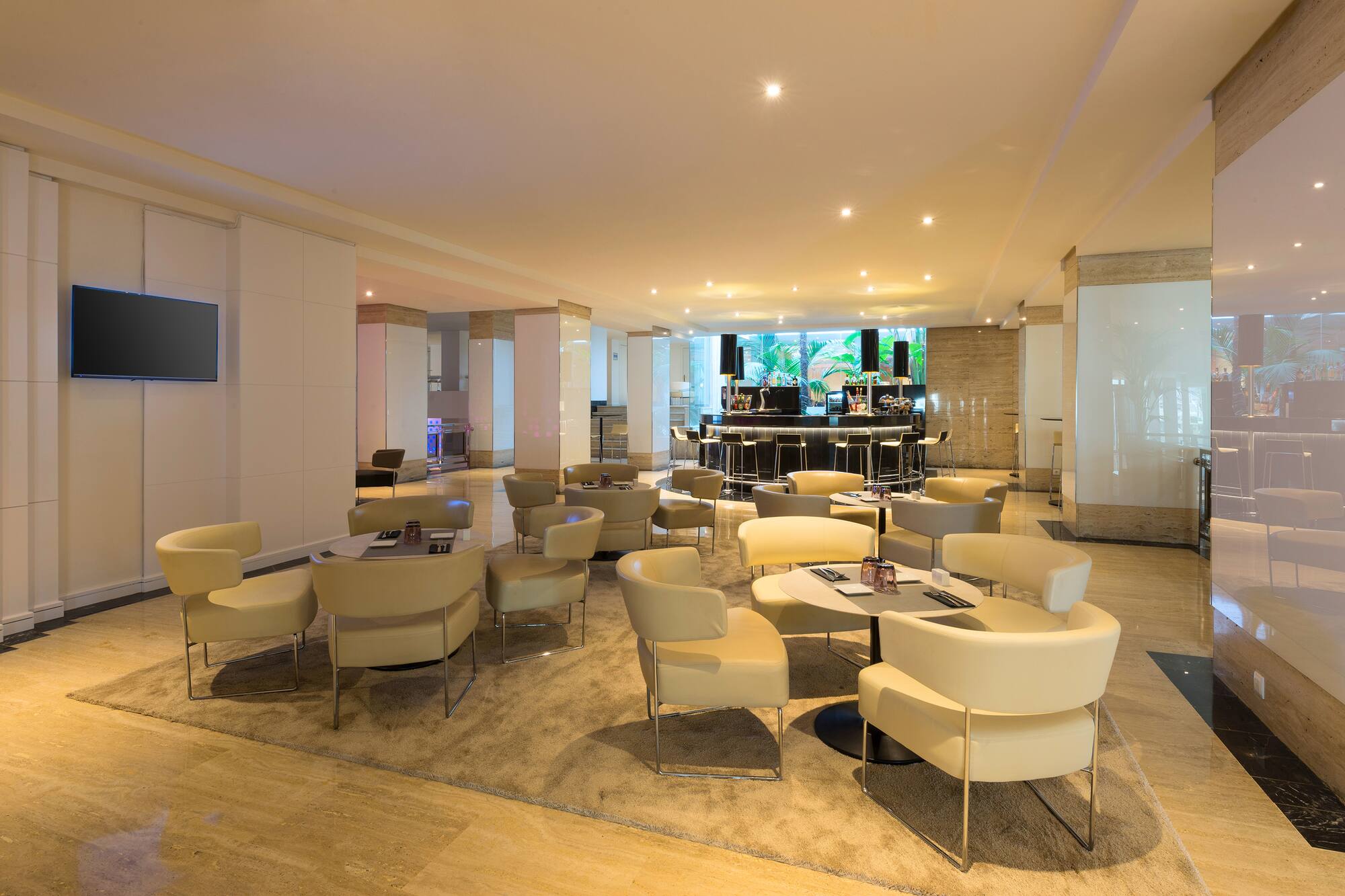 Modern hotel lounge bar with comfortable cream seating and ambient lighting.