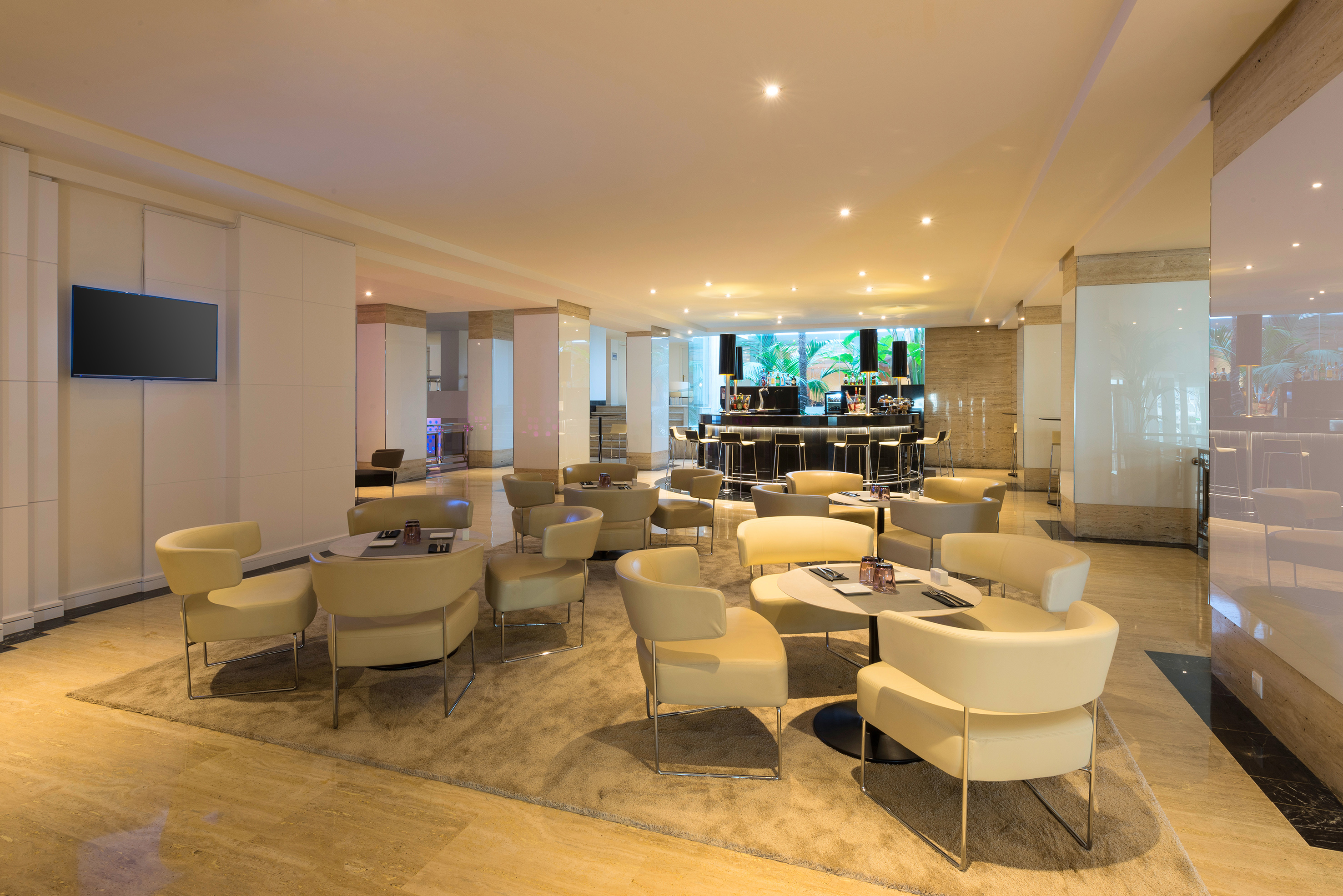 Modern hotel lounge bar with comfortable cream seating and ambient lighting.