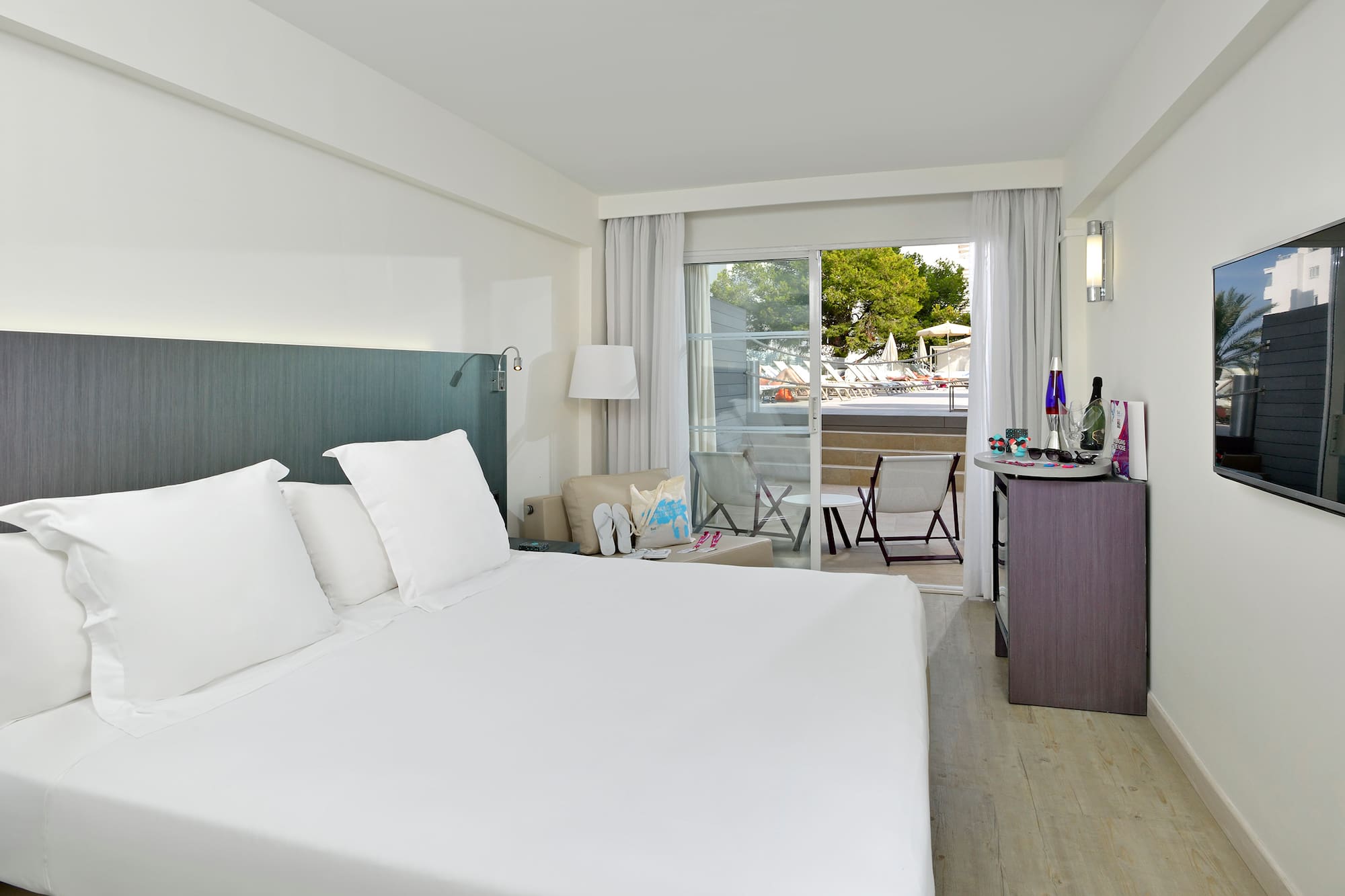 a bed with white sheets and a desk in a hotel room