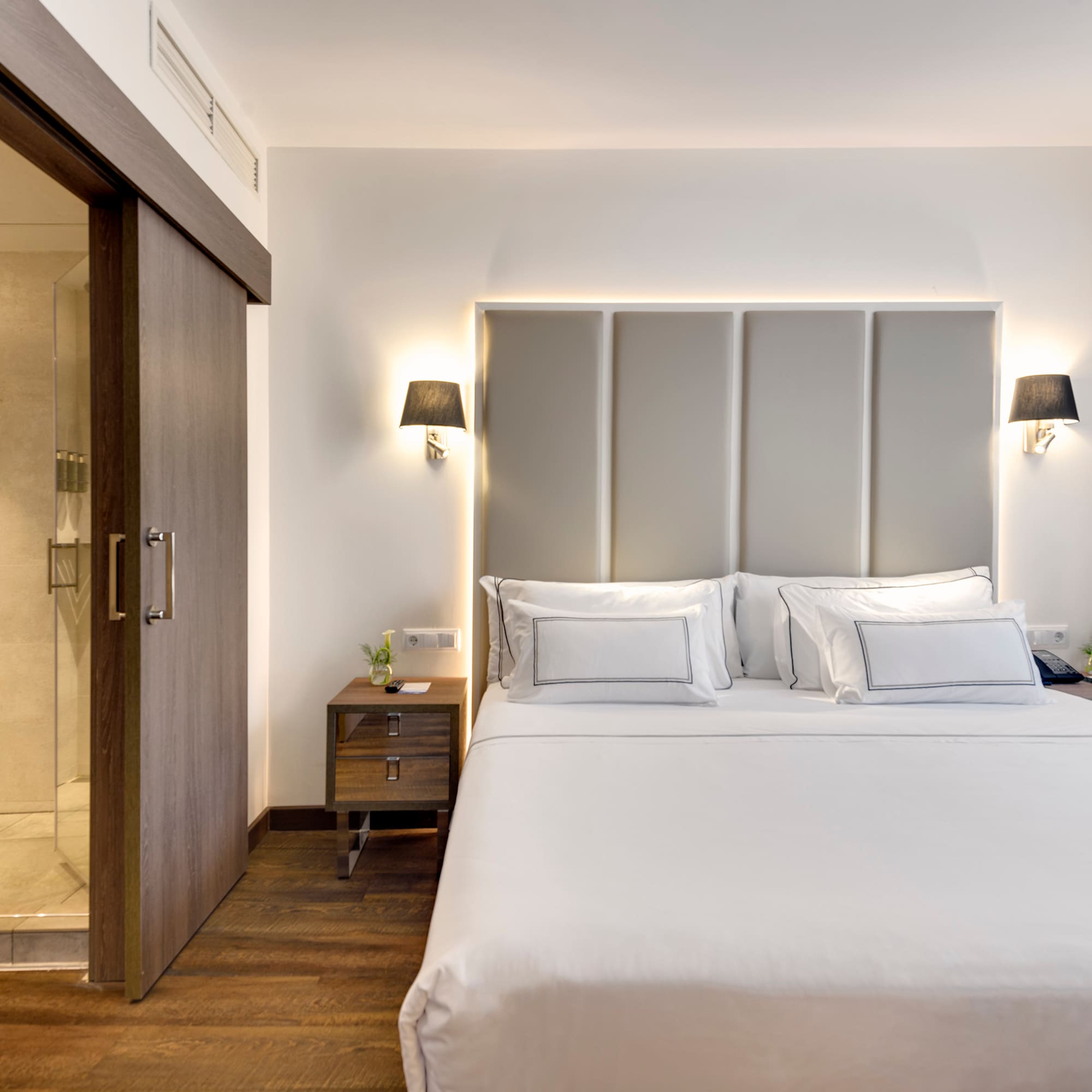 a bed with white sheets and a glass door