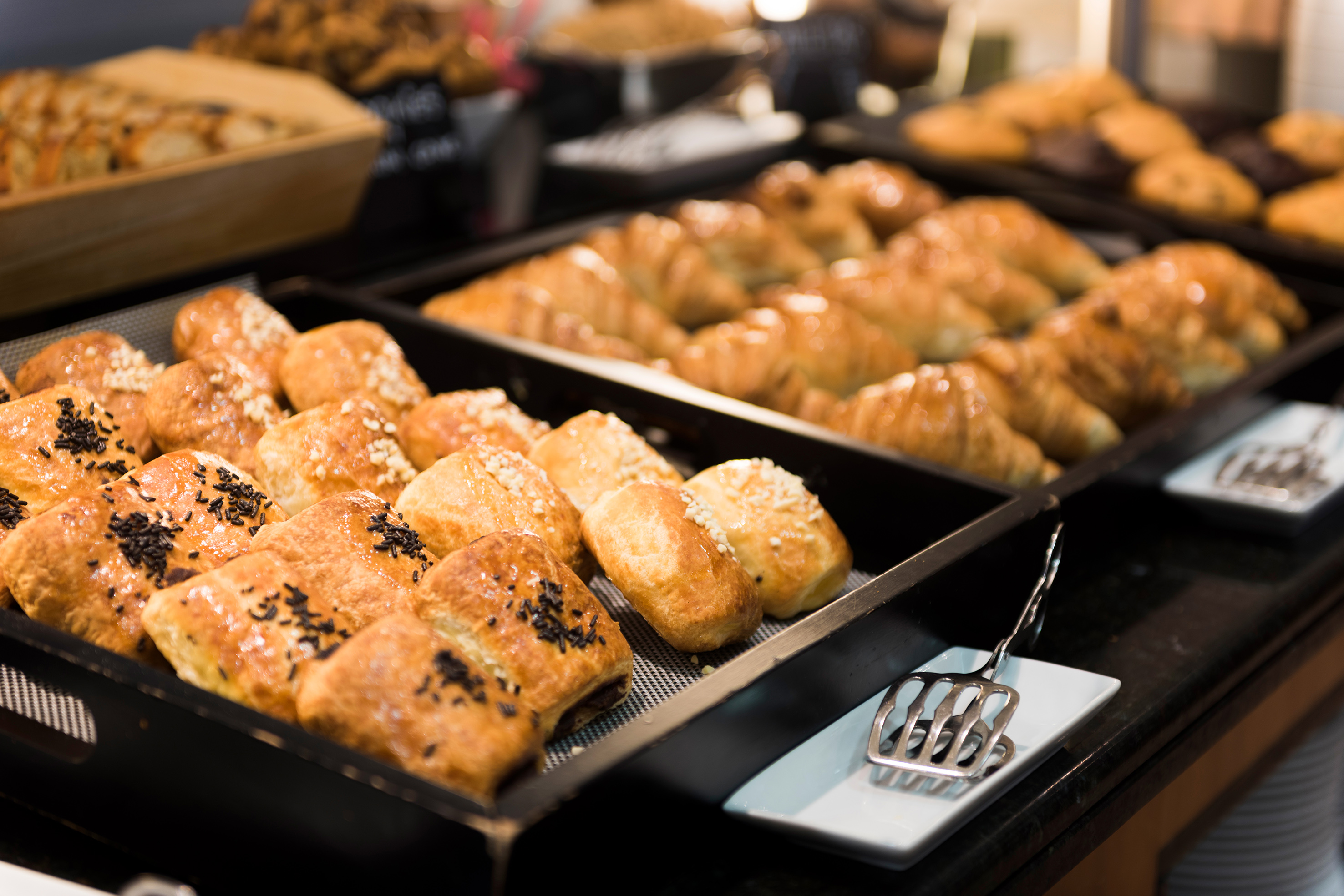 Golden breakfast pastries: chocolate buns, sugared rolls, and glazed croissants.