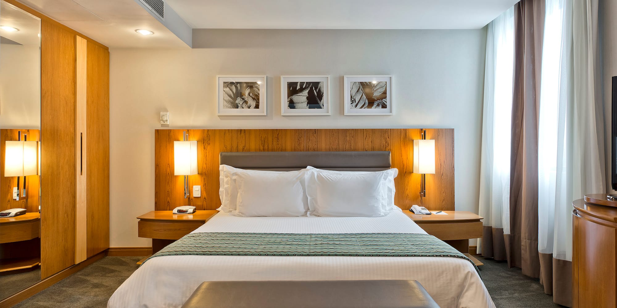 a bed with white pillows and a bench in a hotel room