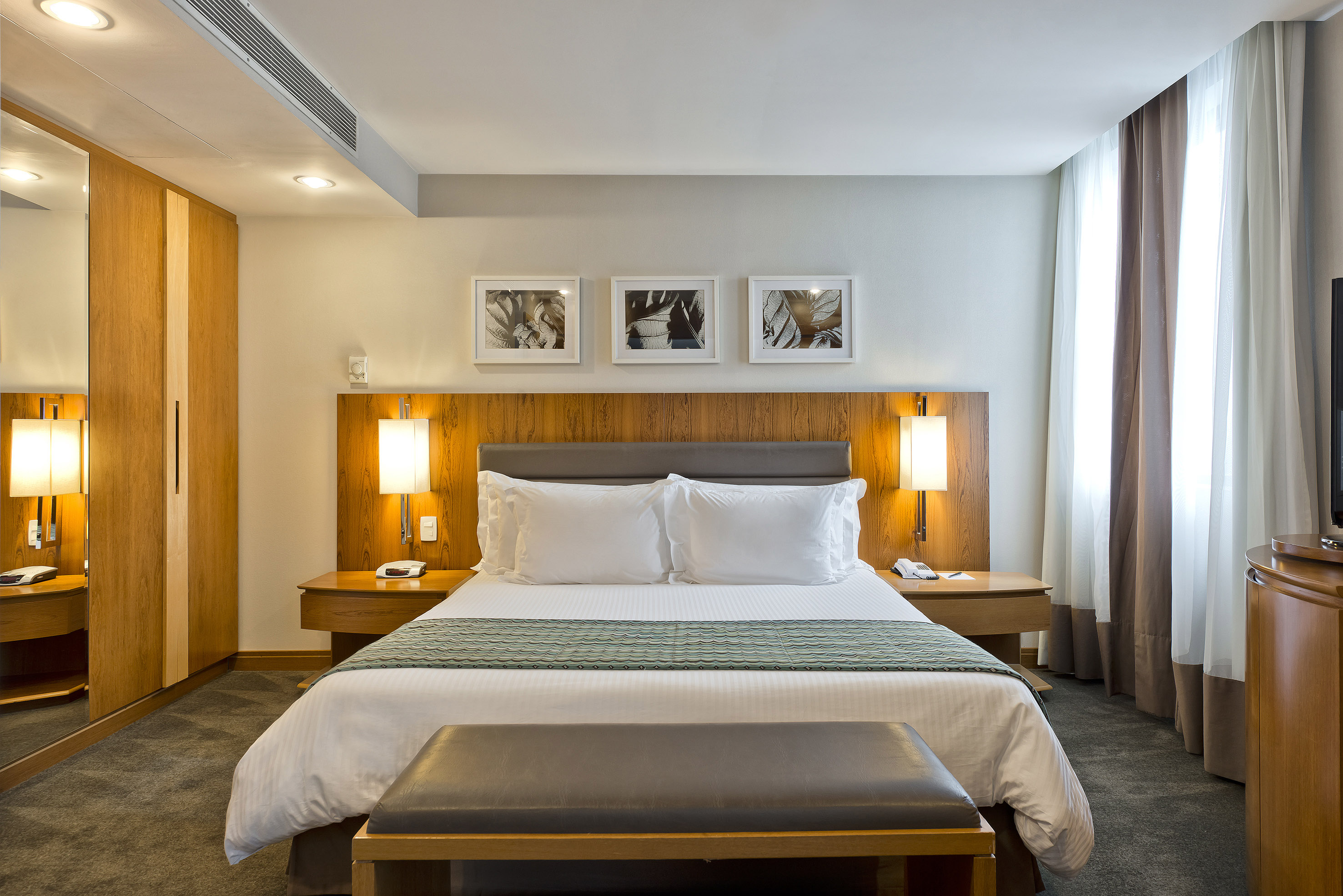a bed with white pillows and a bench in a hotel room