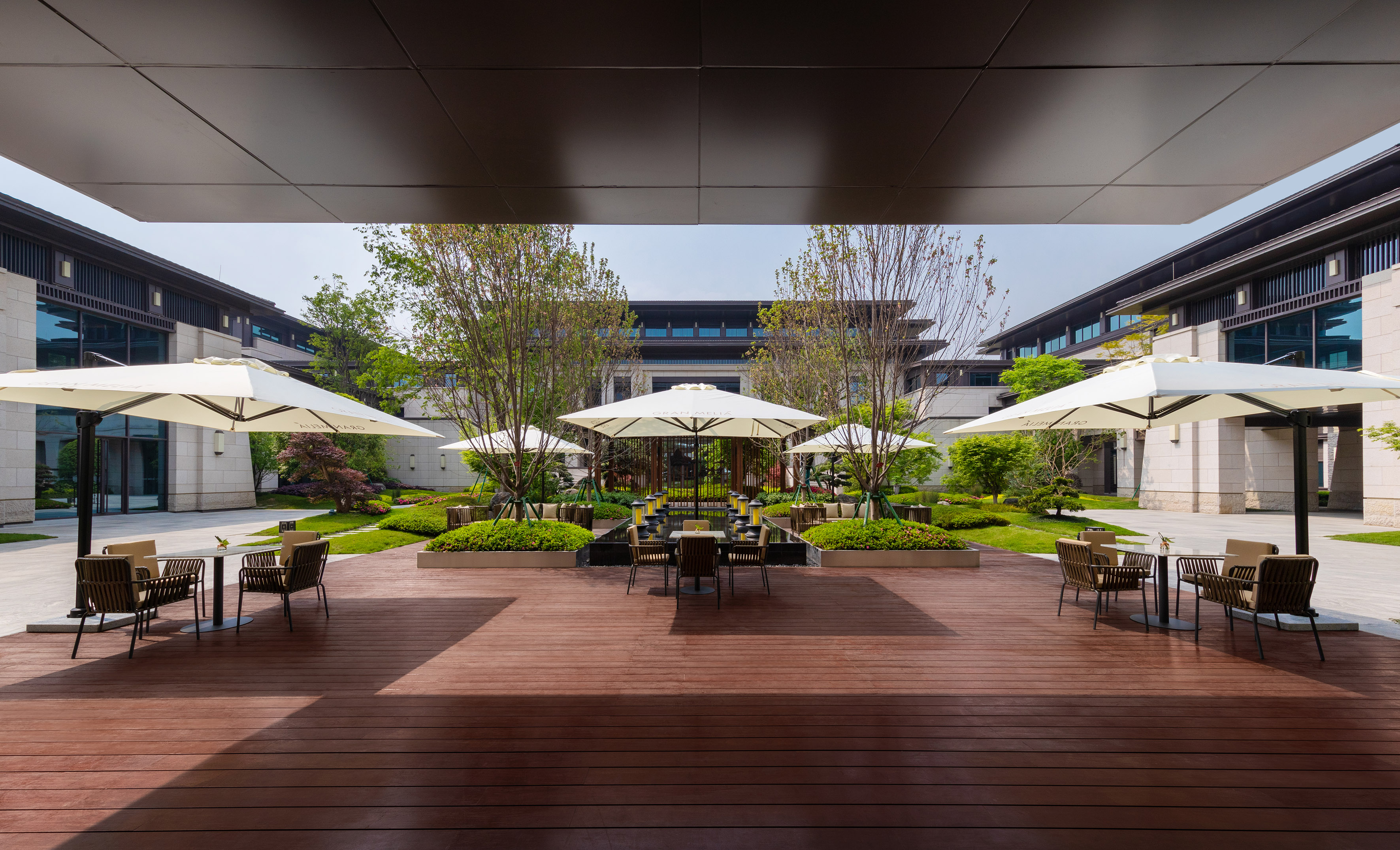 Gran Meliá hotel courtyard with outdoor seating, white umbrellas, and garden.