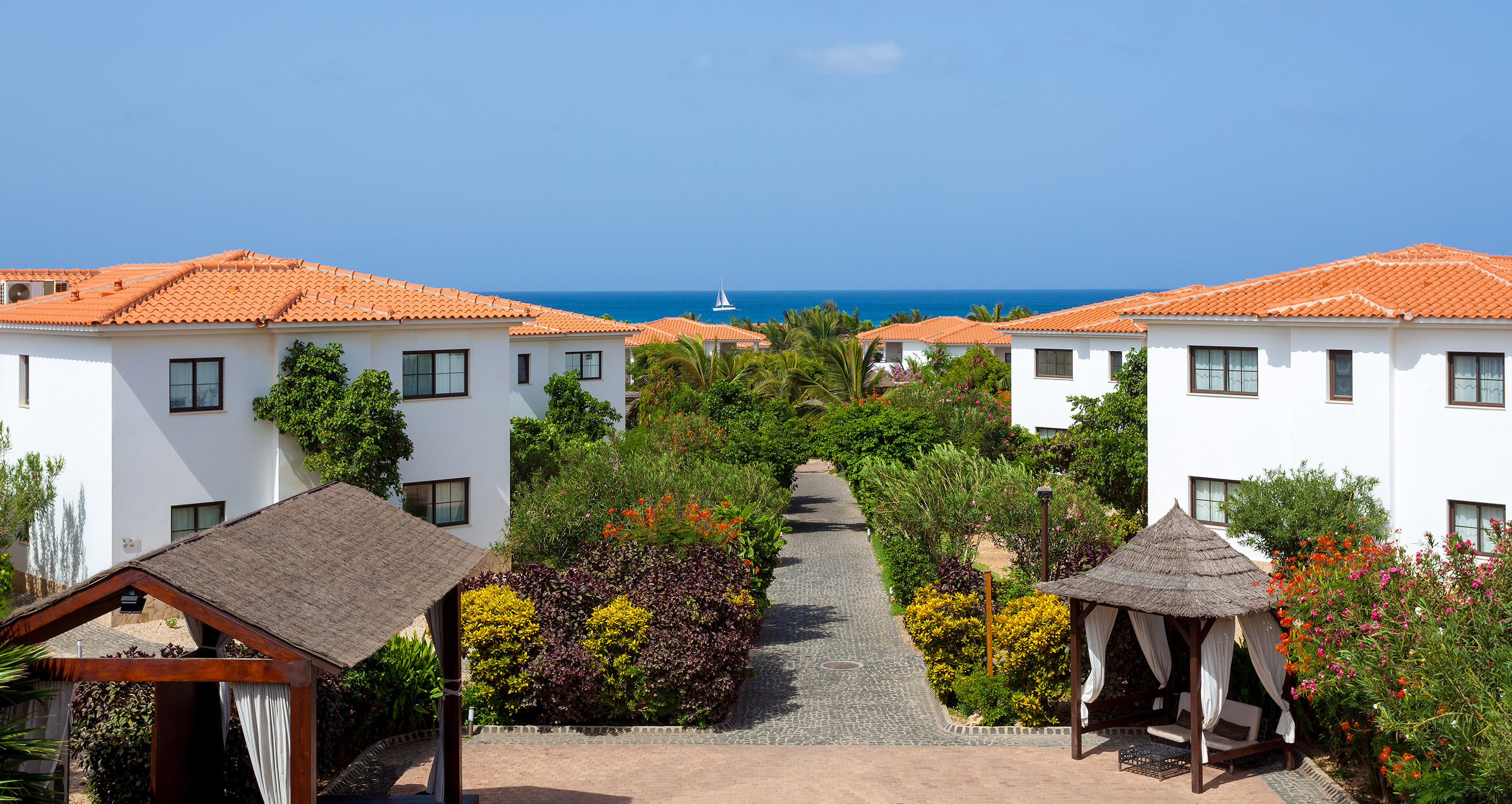 a walkway between buildings with trees and bushes