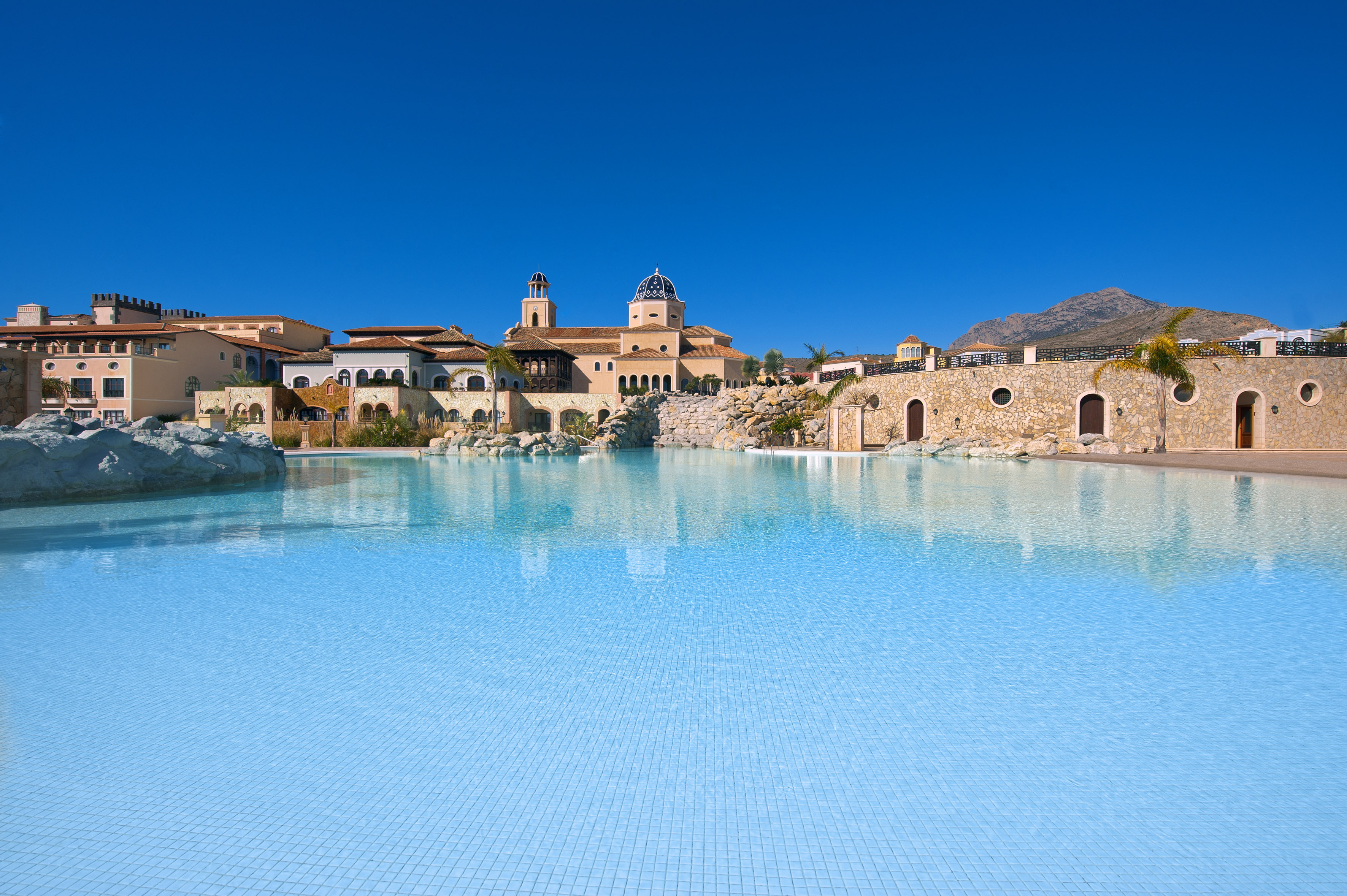 Mediterranean resort pool with traditional architecture and a prominent blue dome.