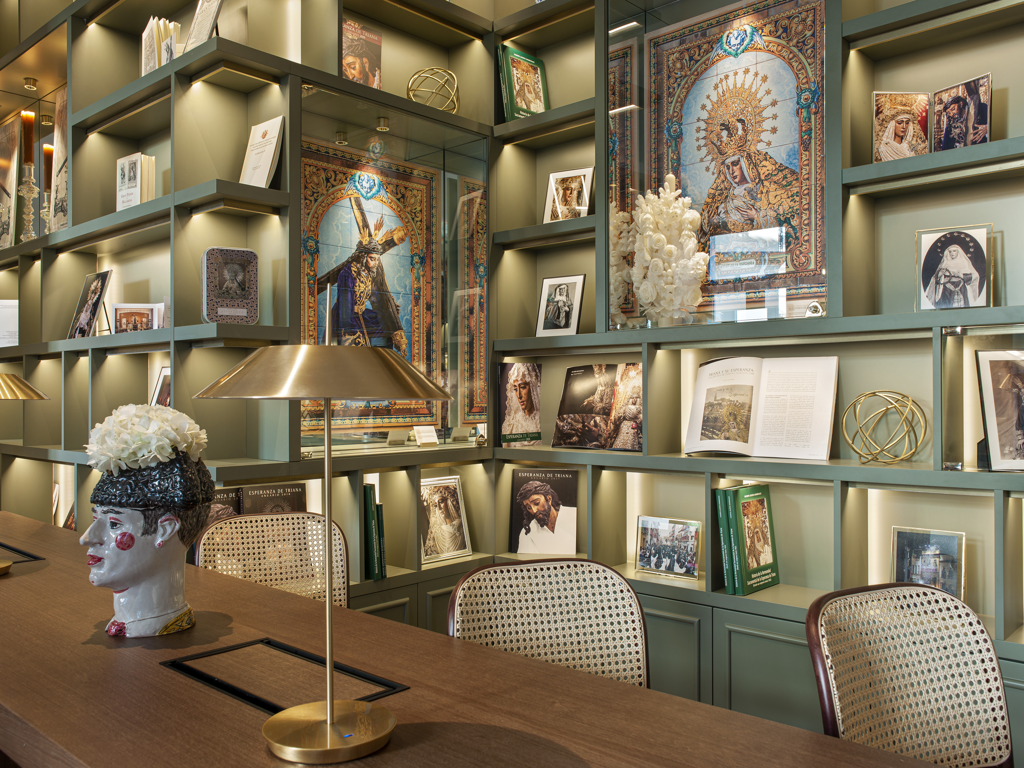 Green library with Esperanza de Triana religious art, books, and desk setup.