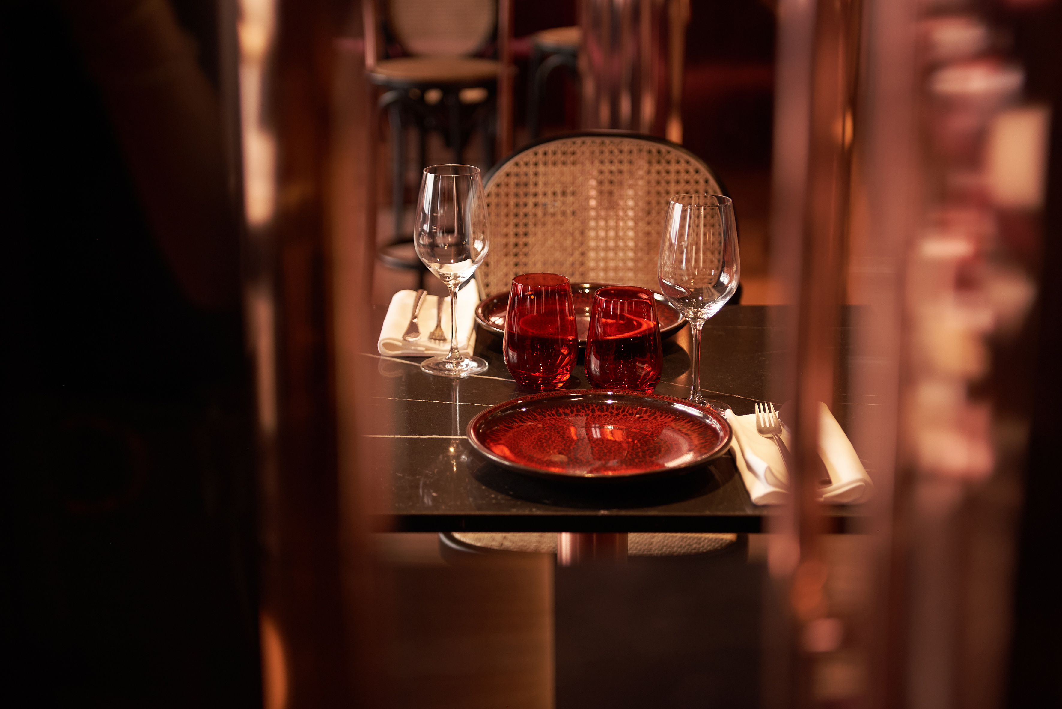 Elegant restaurant table set for two with red dinnerware.