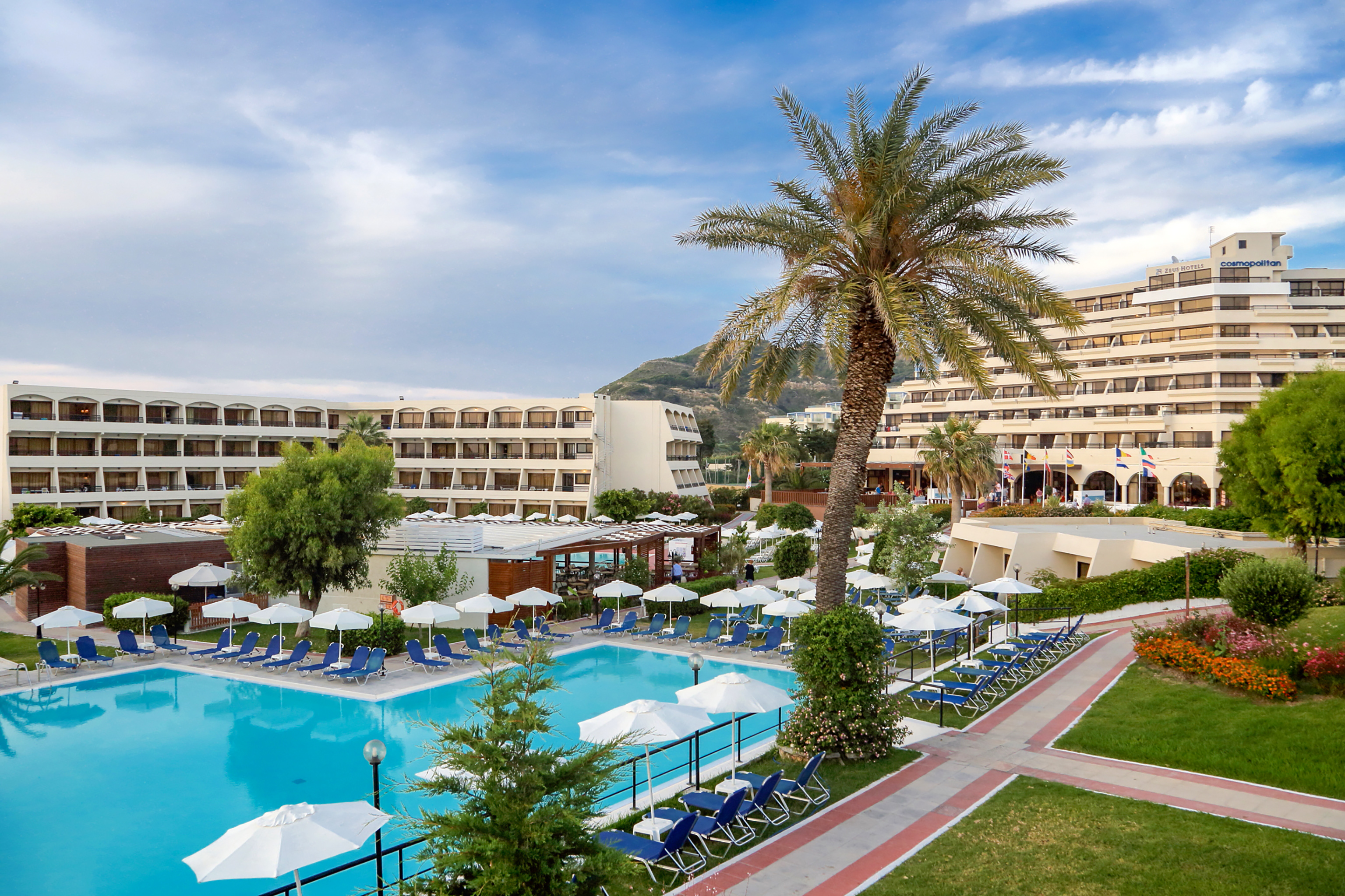 a pool with umbrellas and chairs in front of a hotel