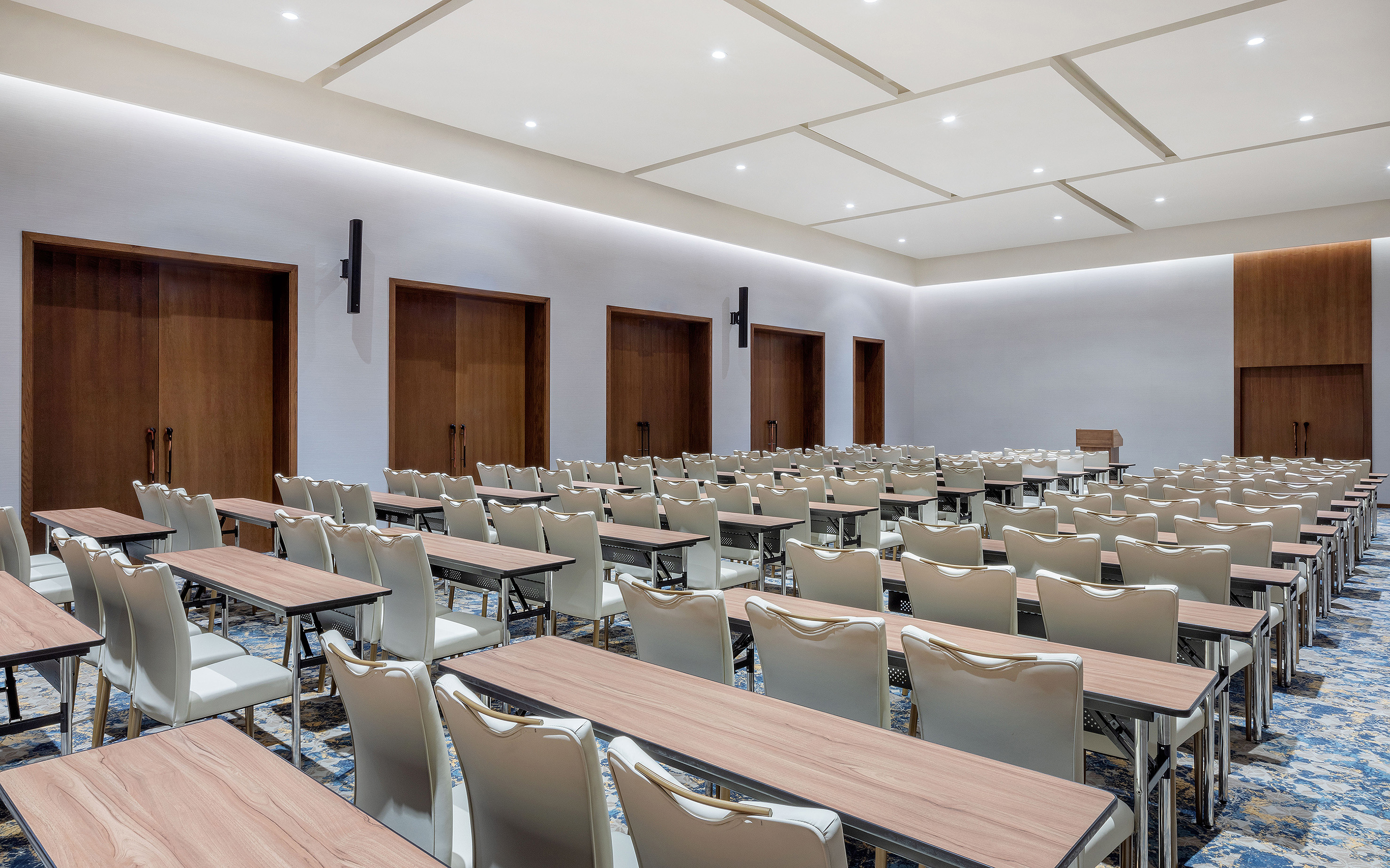 Modern empty event conference room with tables, chairs, and podium.