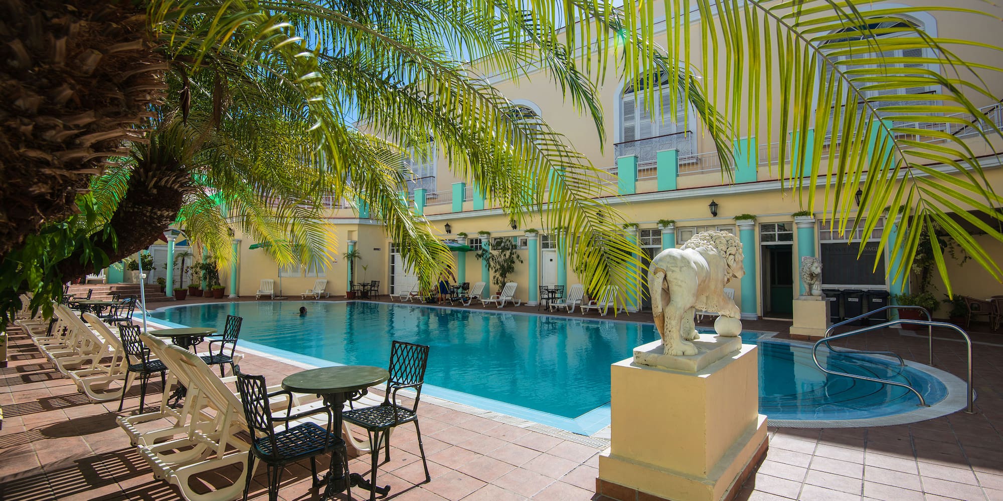 a pool with chairs and tables and chairs in front of a building