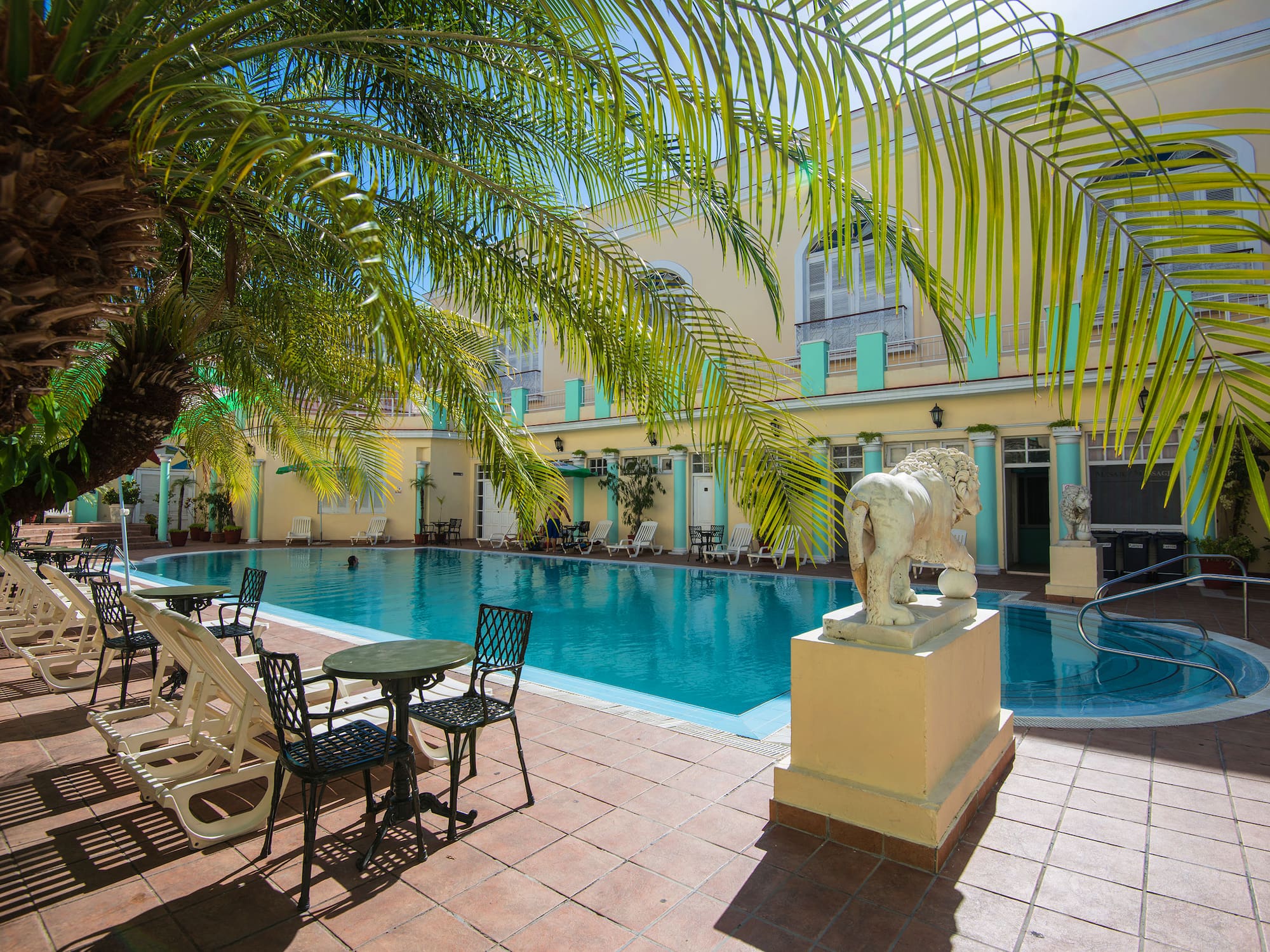 a pool with chairs and tables and chairs in front of a building