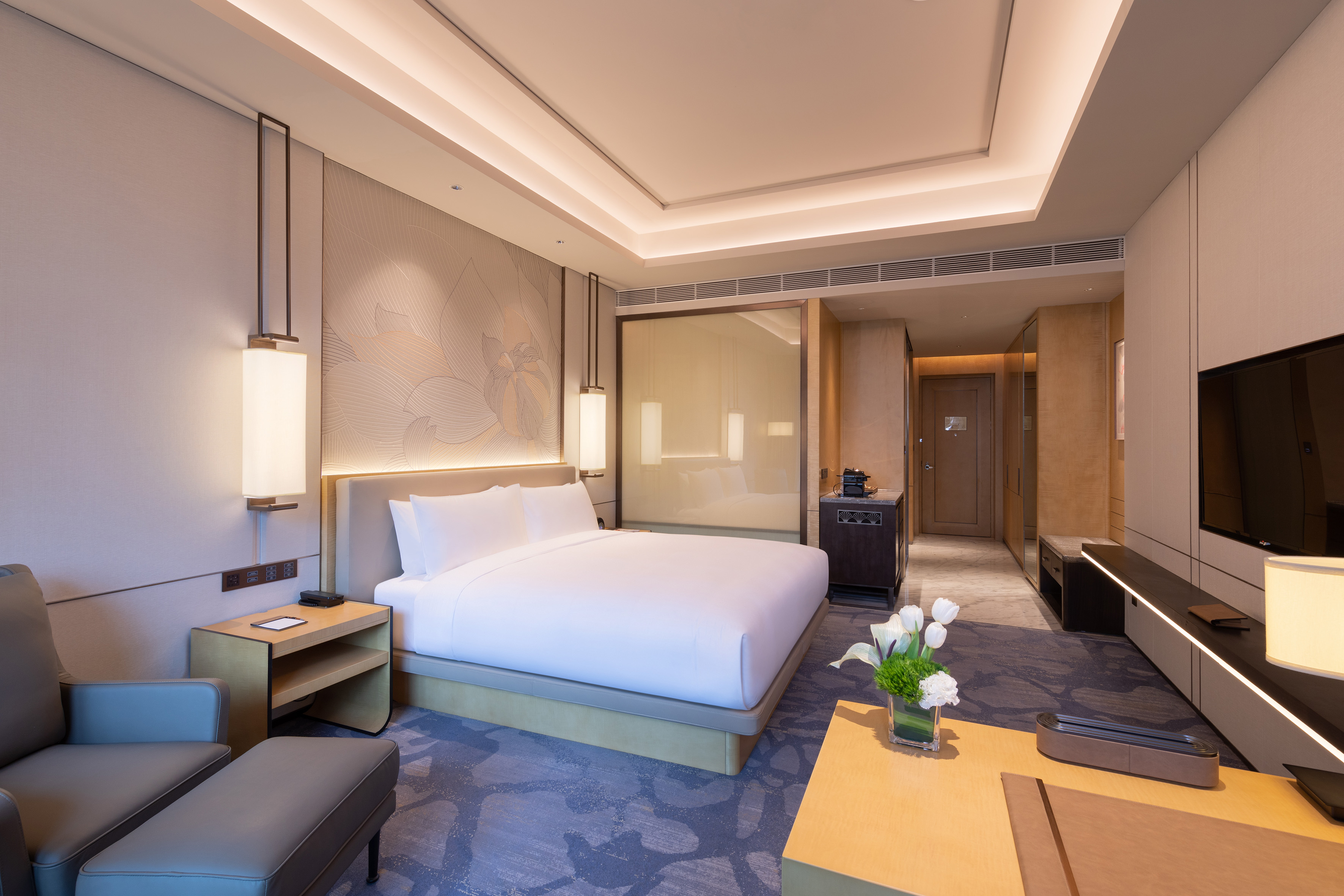 Modern hotel room with king bed, elegant lighting, and seating area.