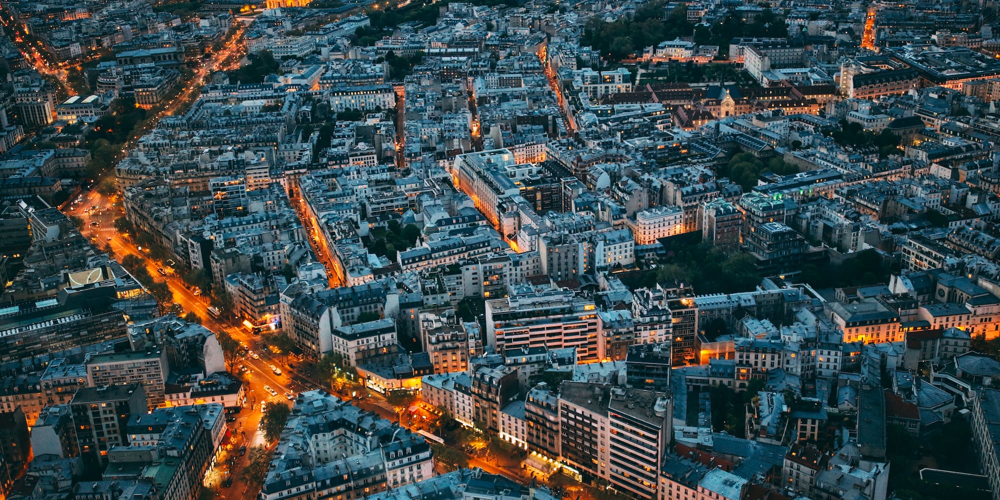 Vista aérea nocturna de París, Les Invalides y calles iluminadas con tráfico.