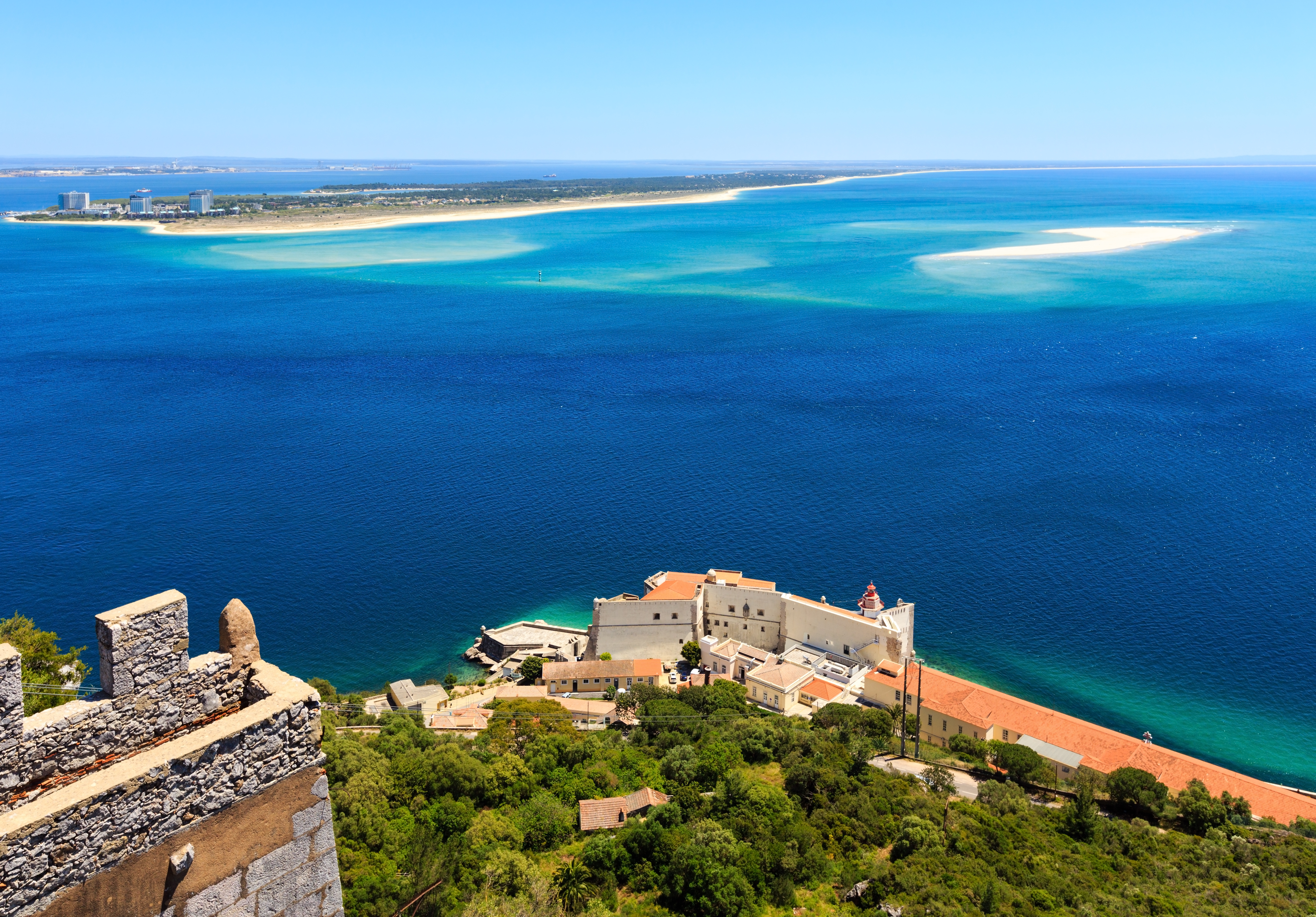 Historic Arrábida monastery overlooking Tróia Peninsula and vibrant blue sea.