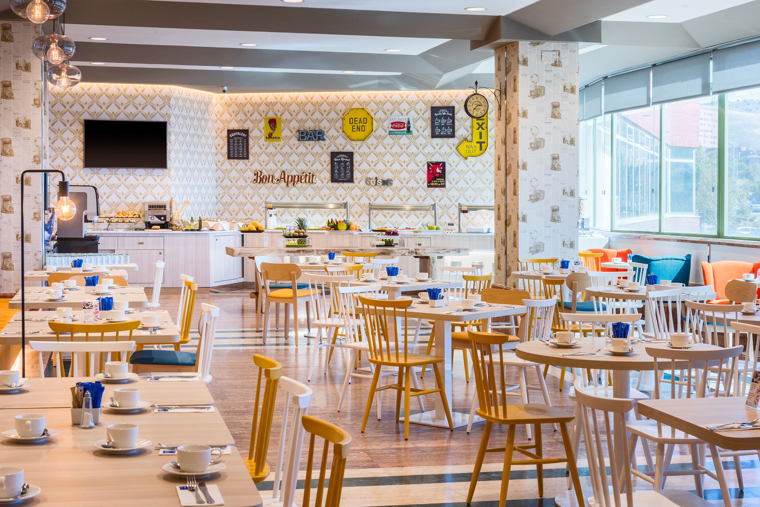 Bright, modern hotel restaurant buffet with colorful tables and chairs.